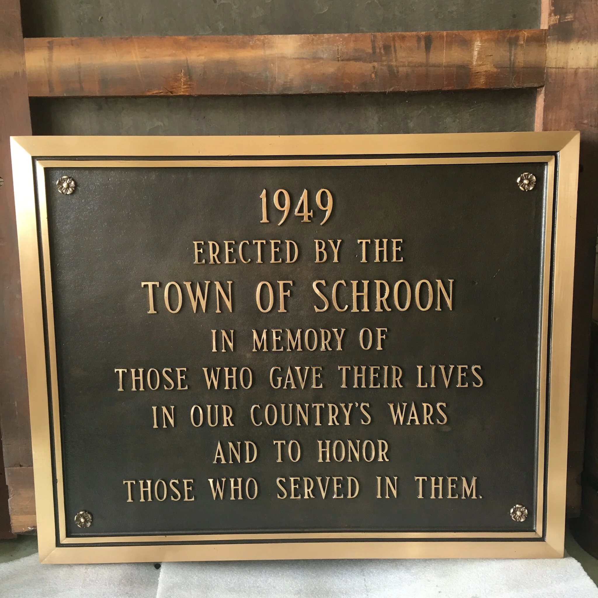 A commemorative plaque with an inscription honoring those who served and sacrificed in the country's wars, erected in 1949 by the town of Schroon.