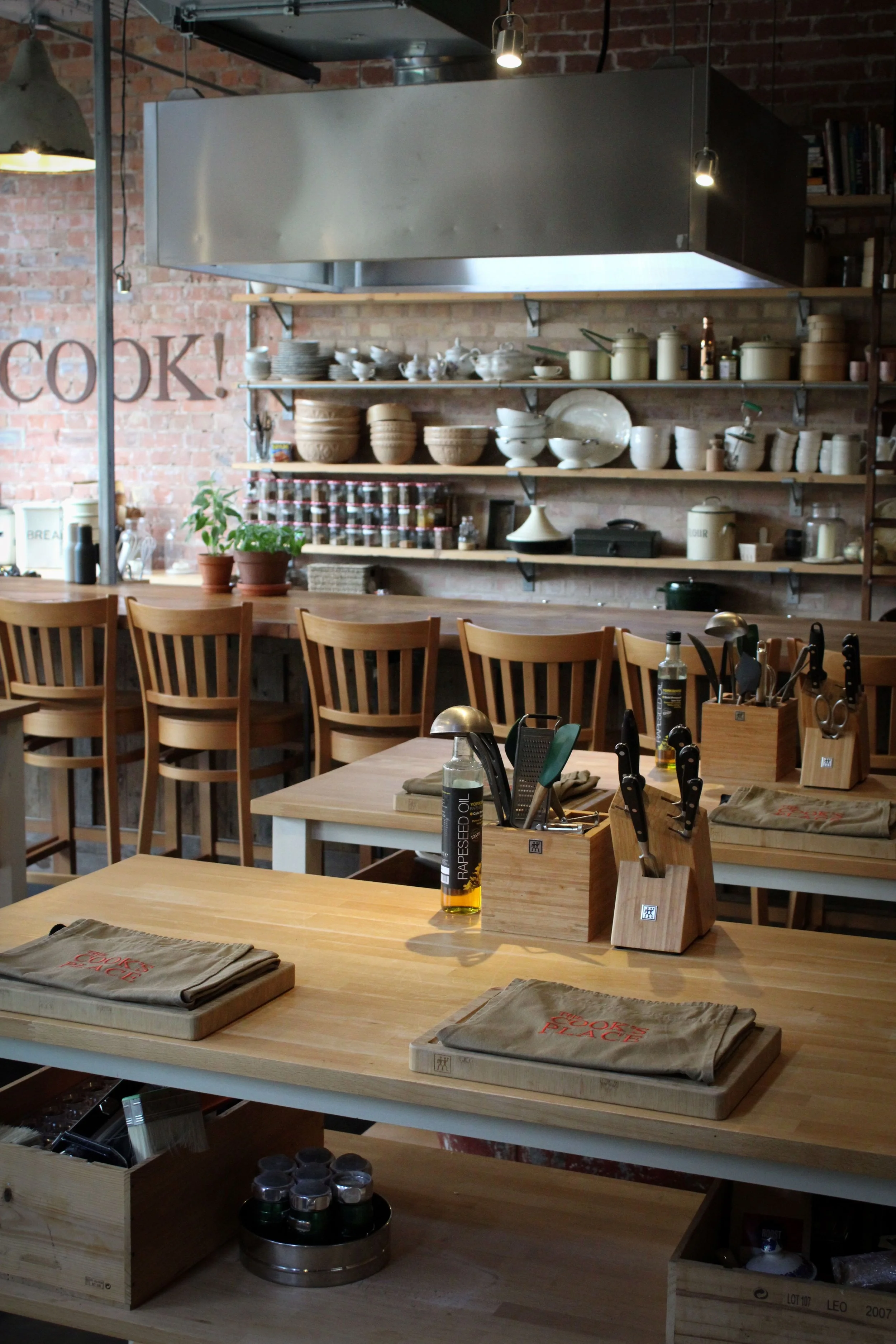 Inside The Cook's Place cookery school in Malton showing cooking benches and shelves stocked with pans and dishes
