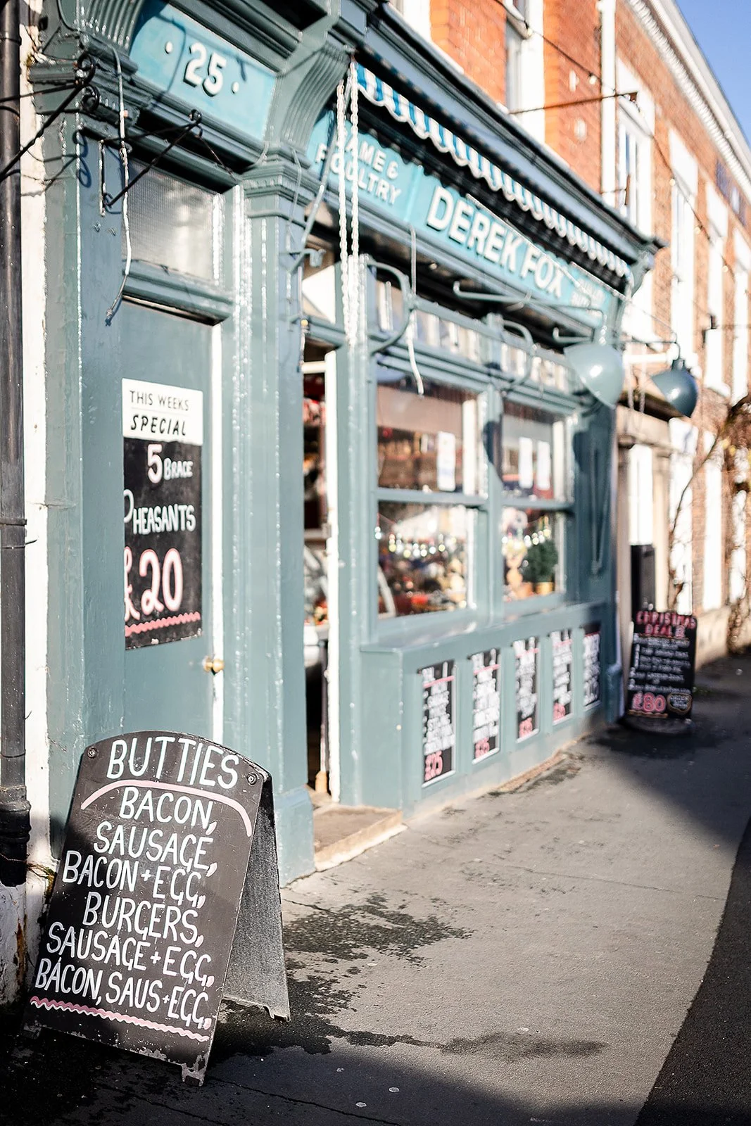 The outside of the Derek Fox Family Butcher's shop with a light blue wooden exterior and two Yorkshire windows.