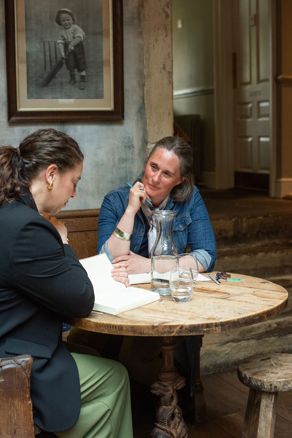 Sarah Oswald, business owner sat at a wooden table talking with a client.