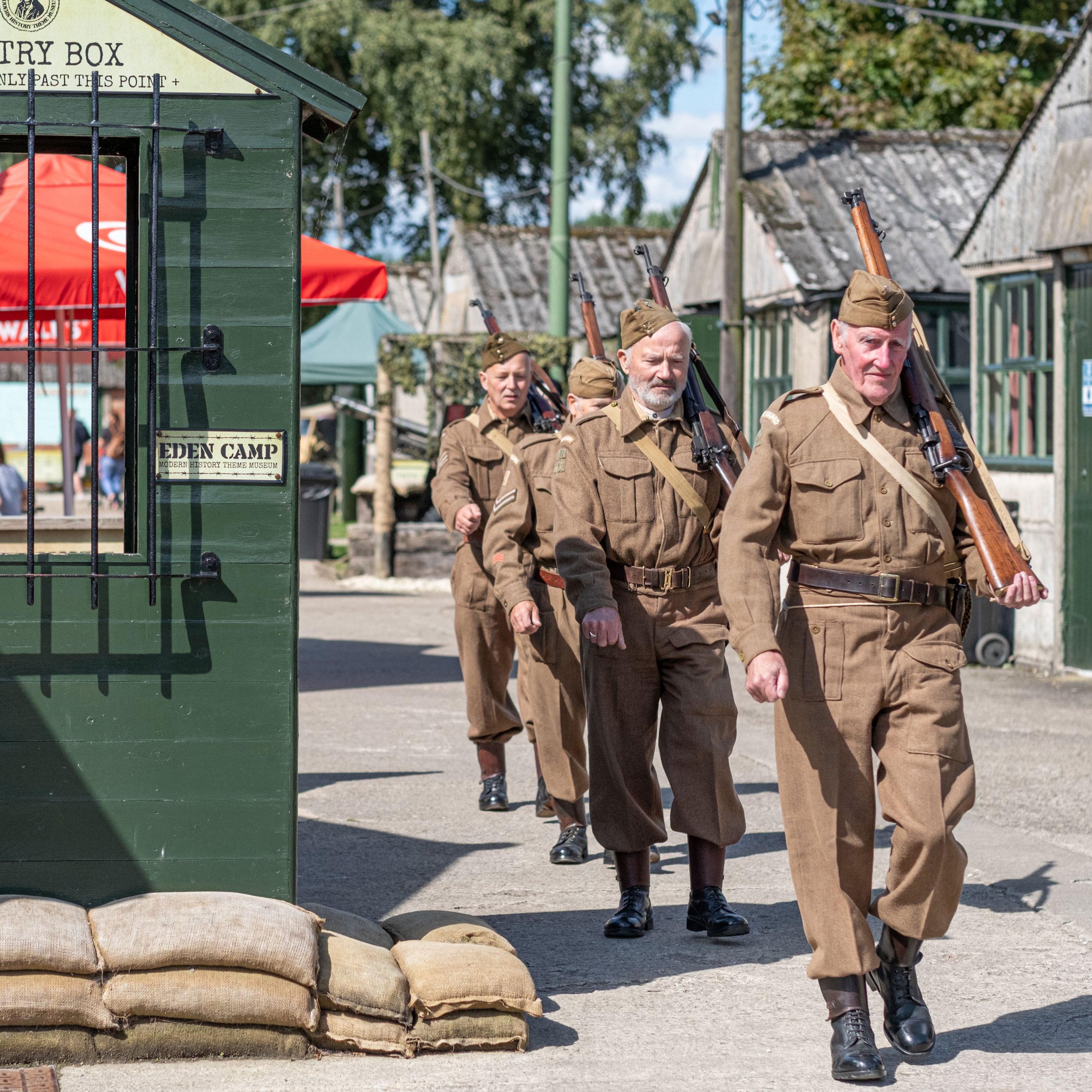 Re-enactment soldiers in uniform carrying replica guns walking through the grounds of the museum.