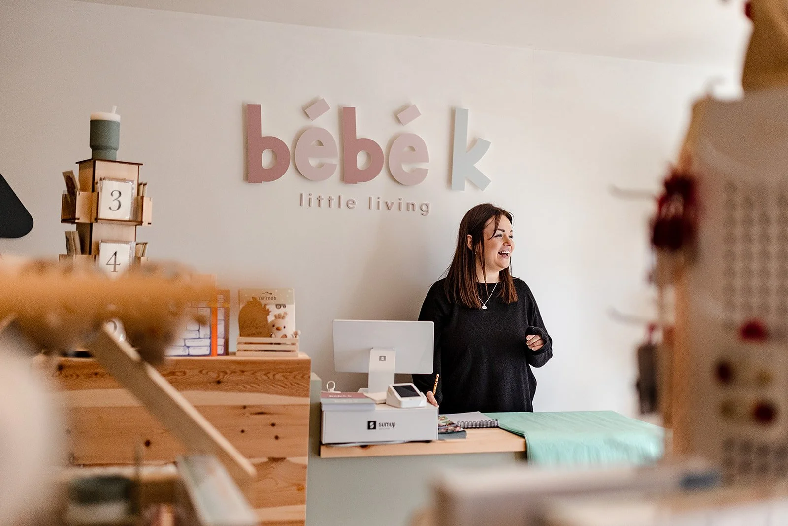 The owner of Bebe K stood behind the counter smiling in the shop