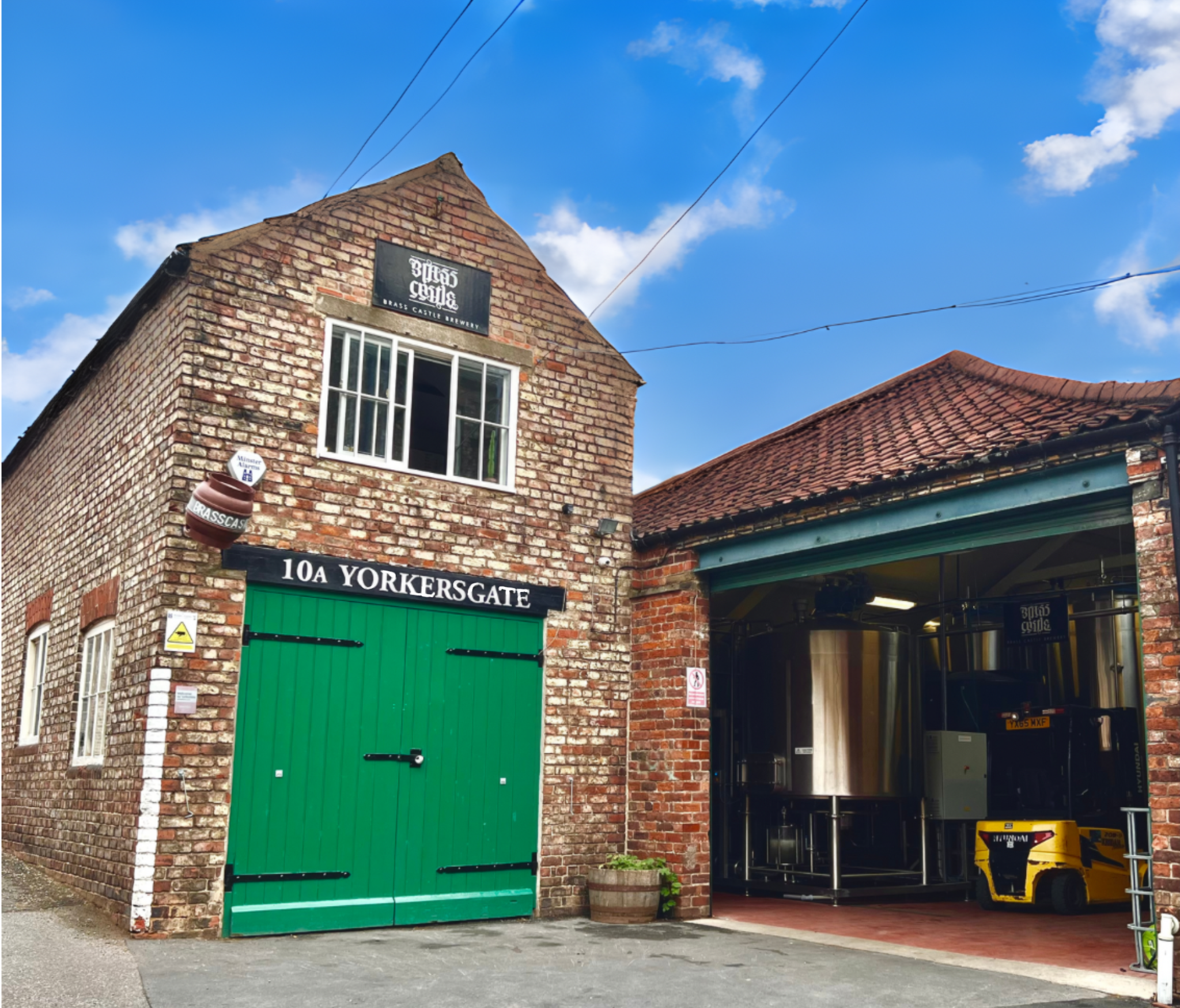 View of the front of the Brass Castle Brewery building displaying the black and white sign "10A Yorkersgate" on a blue sky day