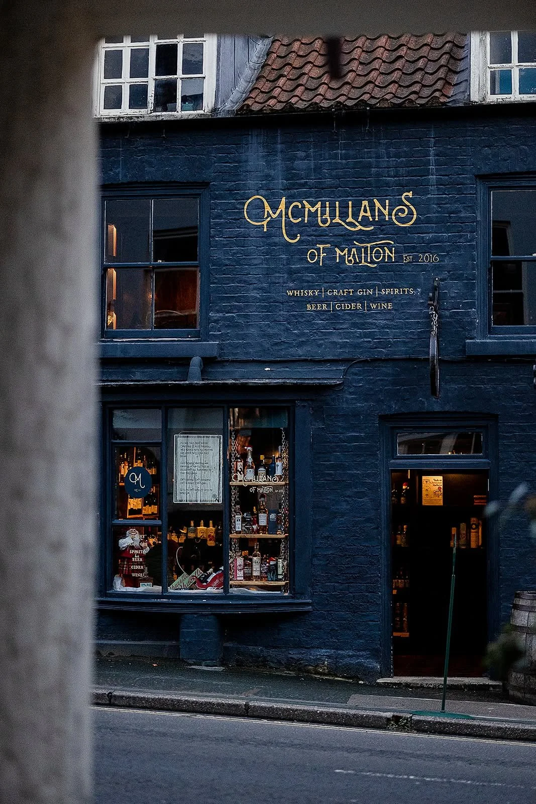 Exterior shot of McMillans of Malton - the building is painted in a dark blue with gold lettering.