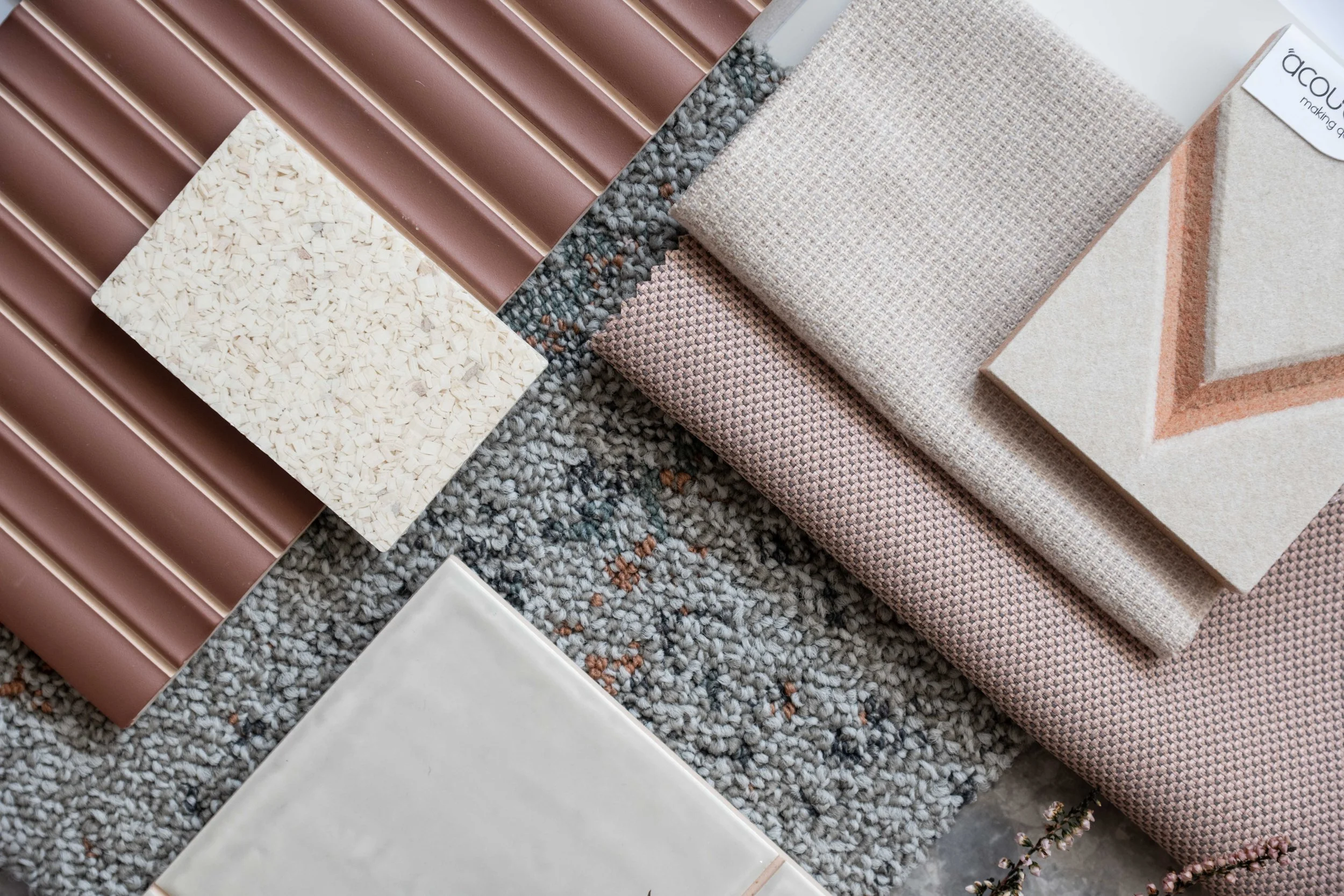 Display of home decor samples including ceramic tiles, fabric swatches, and textured materials.
