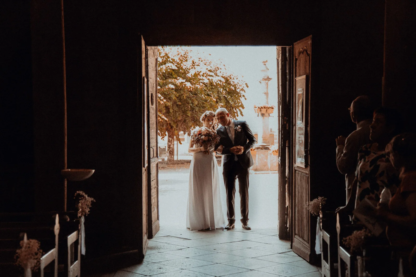 Un couple sortant d'une église après une cérémonie de mariage, avec des invités regardant.