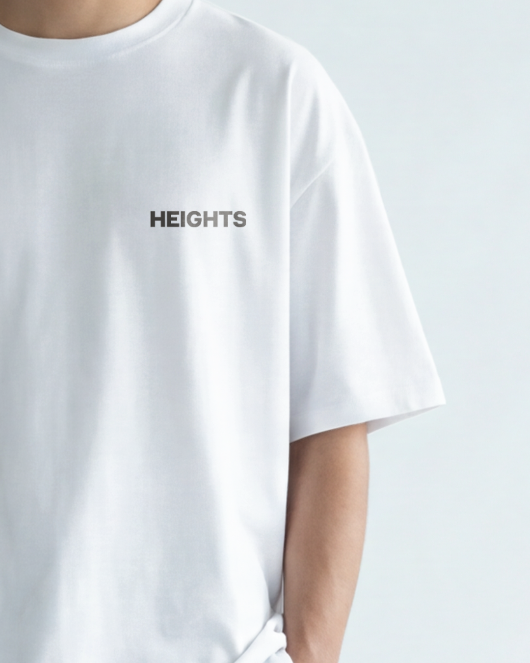 Close-up of a person wearing a white t-shirt with the word 'HEIGHTS' printed on it.