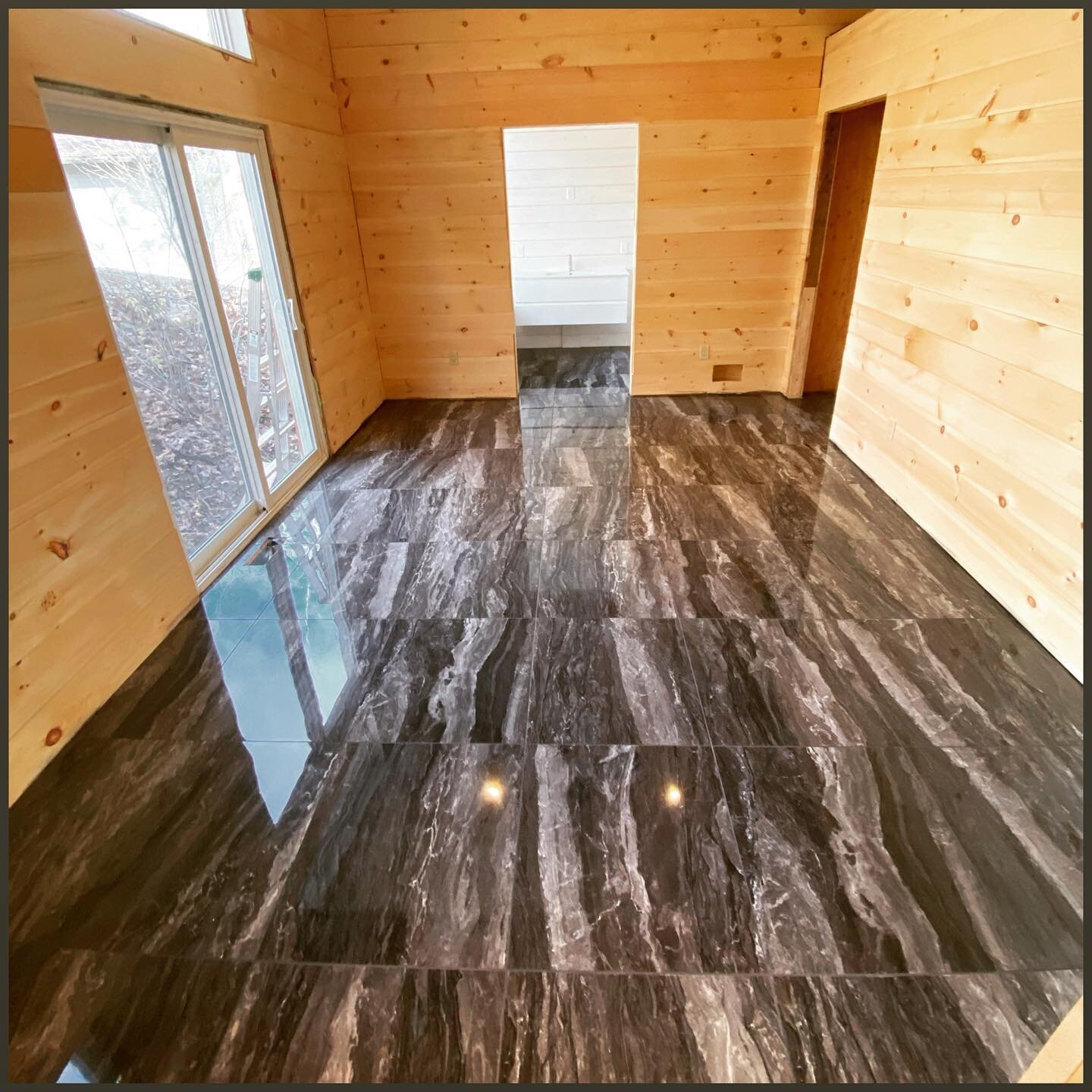 Muskoka AirBnb master bedroom leading to on suite bathroom. 

High gloss tile is awesome for floors you know will have constant foot traffic 🦶 

#muskoka #airbnb #highgloss #tilefloors #tiledesign #cottagestyle  #pine  #24x24 #tileinstallation #tile