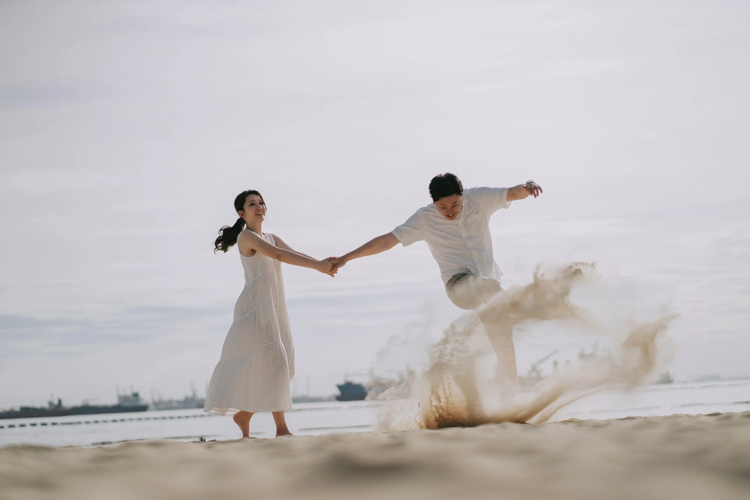 In a picturesque beach setting, a radiant couple revels in their pre-wedding photoshoot, capturing not just images but memories that'll last a lifetime. Clad in casual attire—she in a flowy sundress and he in a relaxed button-down shirt and khaki sho