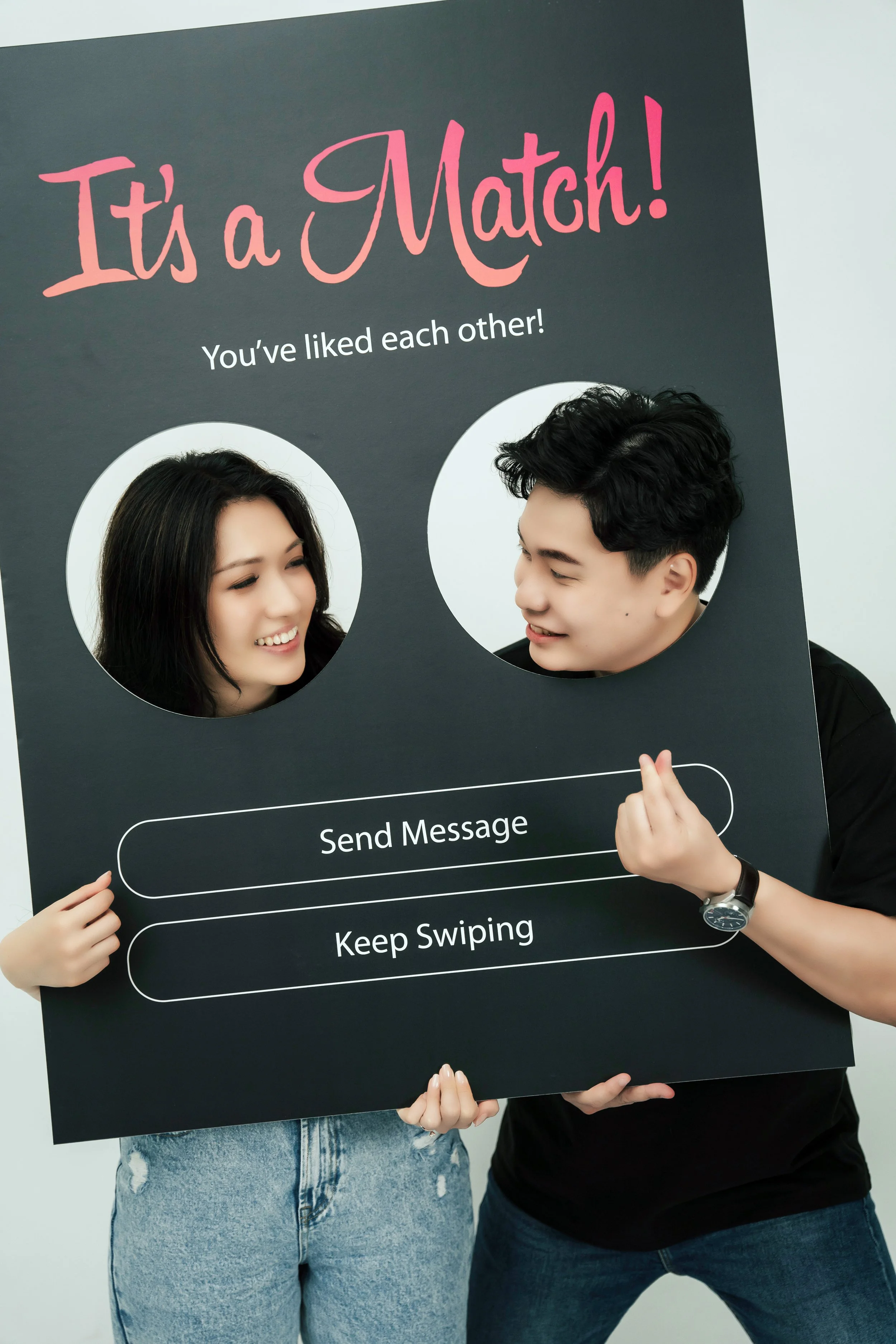 In a sleek photography studio, a couple opts for a unique twist on the traditional pre-wedding photoshoot by incorporating elements that tell the story of their modern love. Against a crisp white backdrop, they stand in casual attire—comfortable yet 