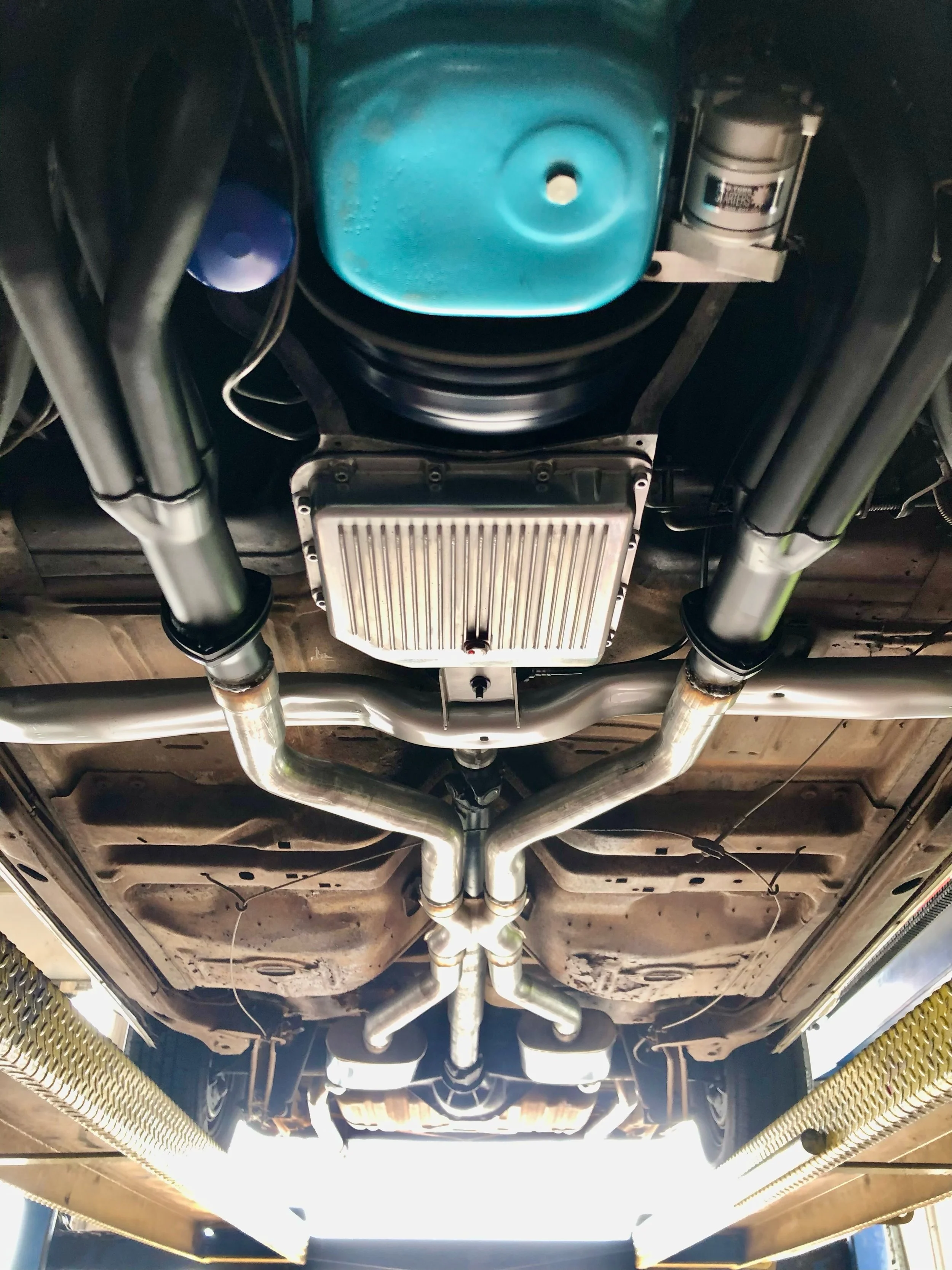 Under the car, showing exhaust system, oil pan, transmission component, and suspension parts.