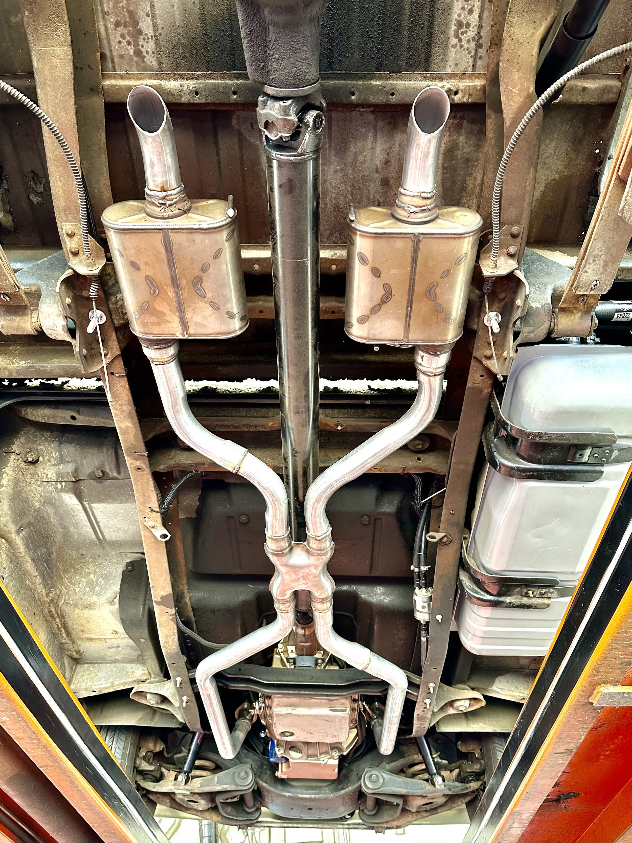 Underside view of a car's exhaust system showing dual mufflers and pipes.