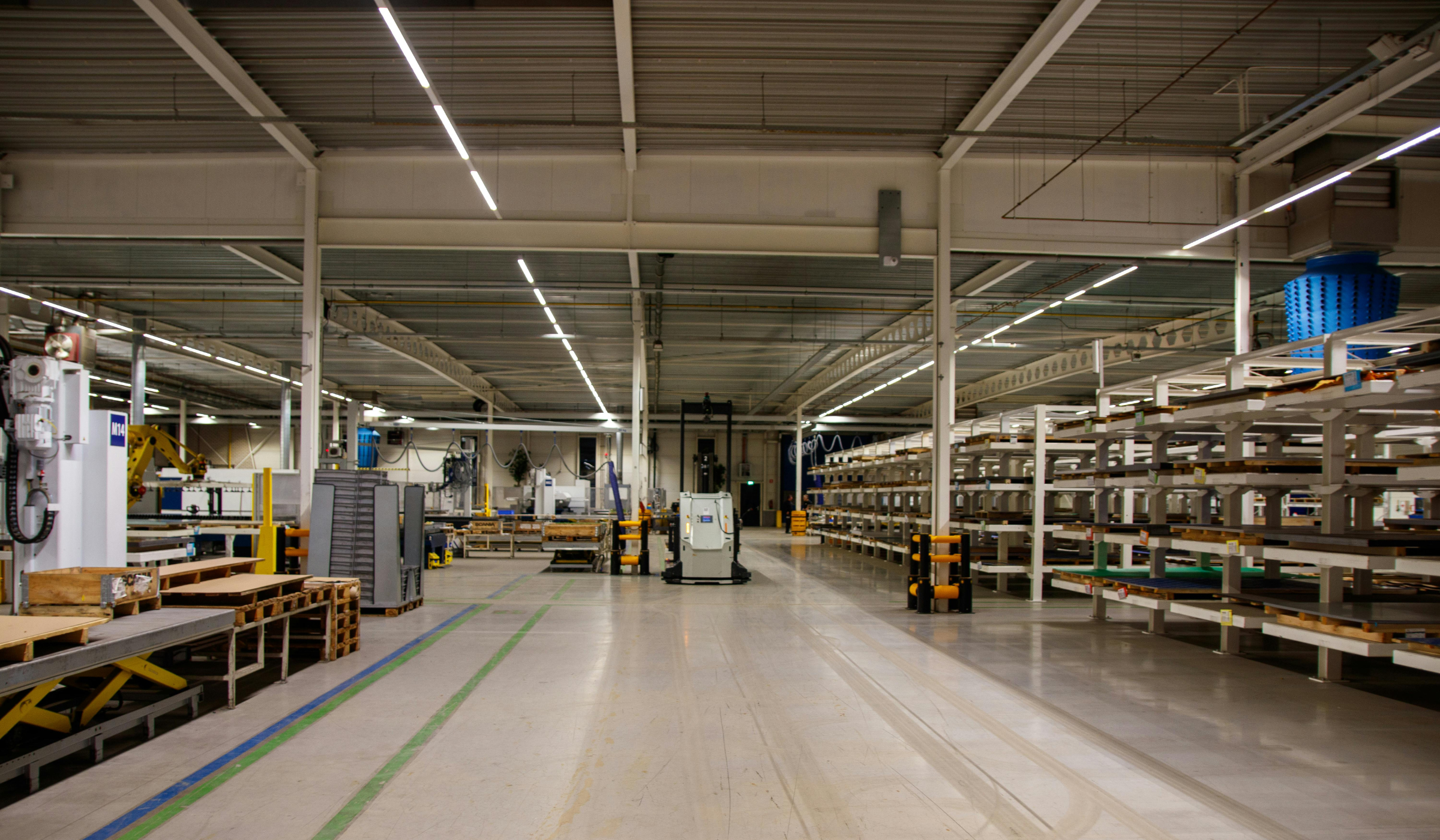 Empty industrial warehouse or manufacturing facility with shelves, pallets, and machinery.