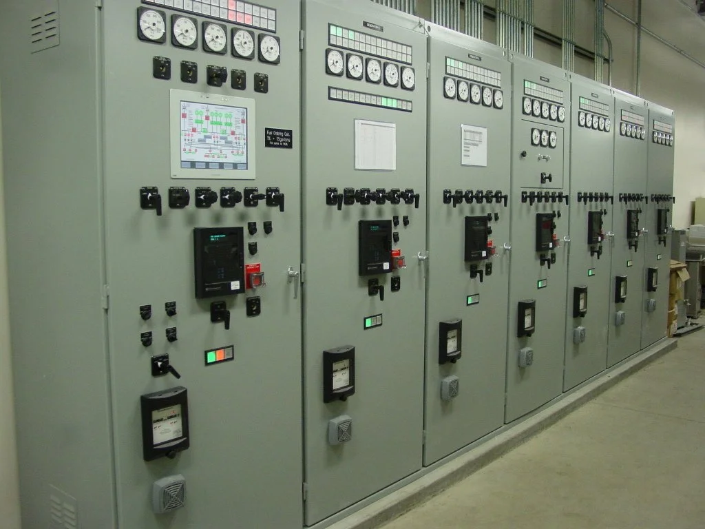Electrical control panels with gauges, switches, and digital displays in an industrial setting.