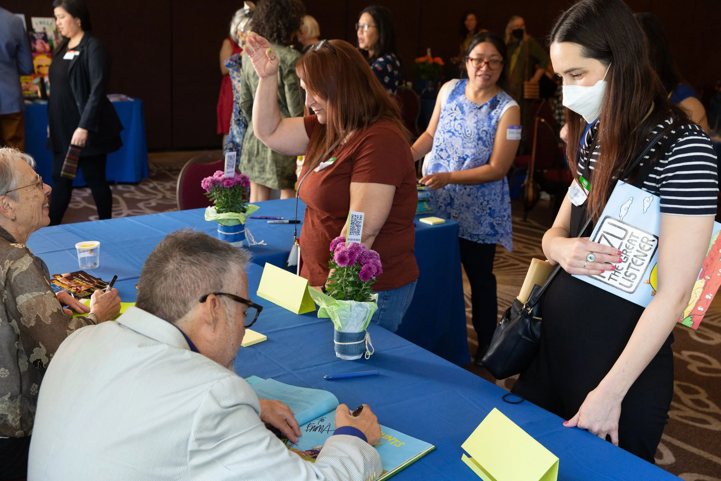 L to R: Author Caroline Arnold listens as she signs a book for Kristen Valenzuela, author-illustrator Joe Cepeda signs a book for Emmarose Alef. (Josh Steichmann)