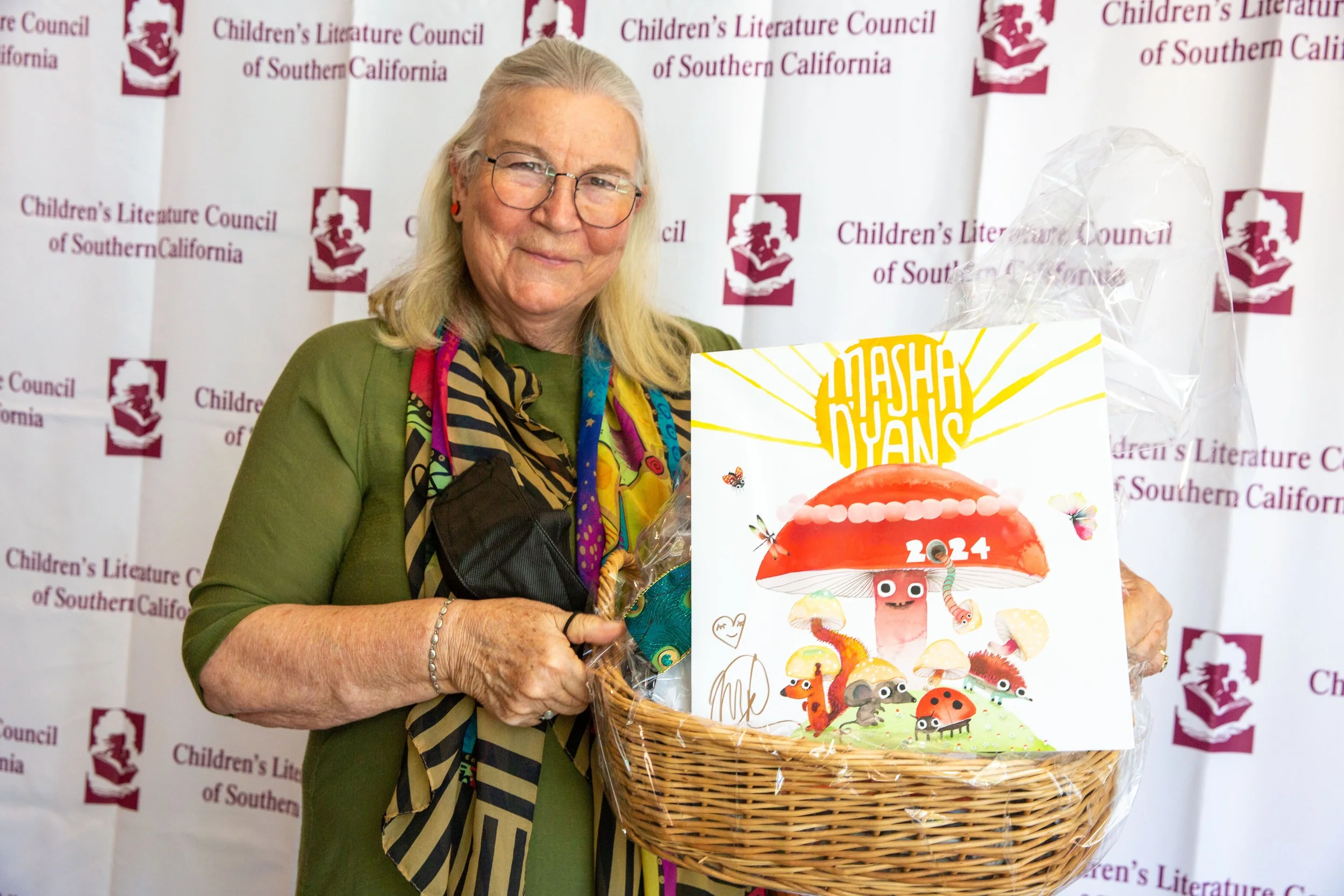 Gail Panatier holds up a basket with Masha D'yan's 2024 calendar prominently displayed. (Josh Steichmann)