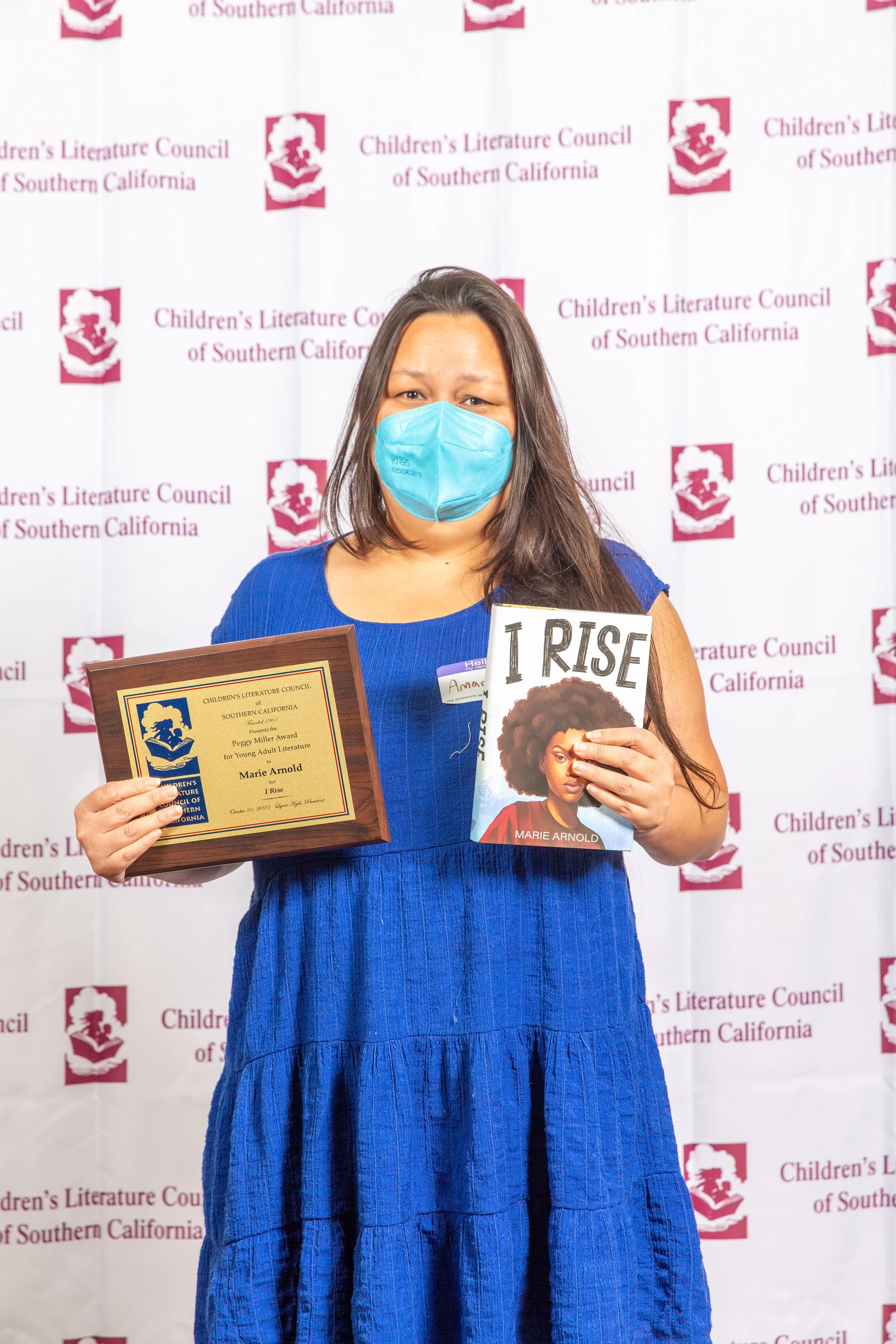 Awards Committee Member Amanda Santos holds Marie Arnold's award winner plaque and a copy of Arnold's winning novel, I Rise. (Josh Steichmann)