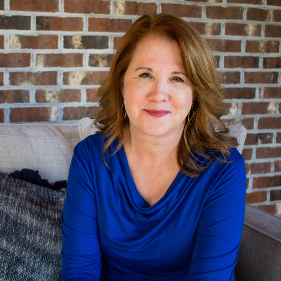 Author Dana Middleton smiles at the camera, wearing a blue top. Her light brown hair is side parted and shouder length