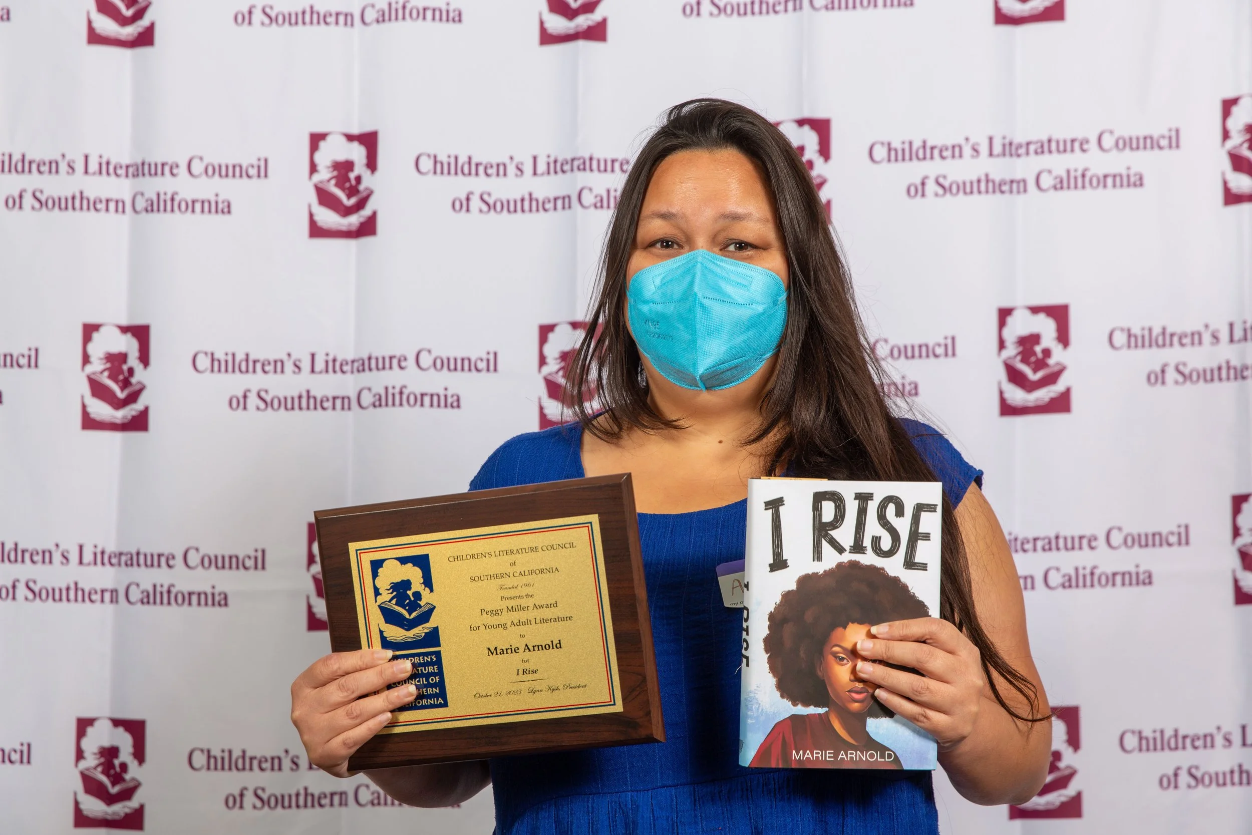 Awards Committee Member Amanda Santos holds Marie Arnold's award winner plaque and a copy of Arnold's winning novel, I Rise. (Josh Steichmann)