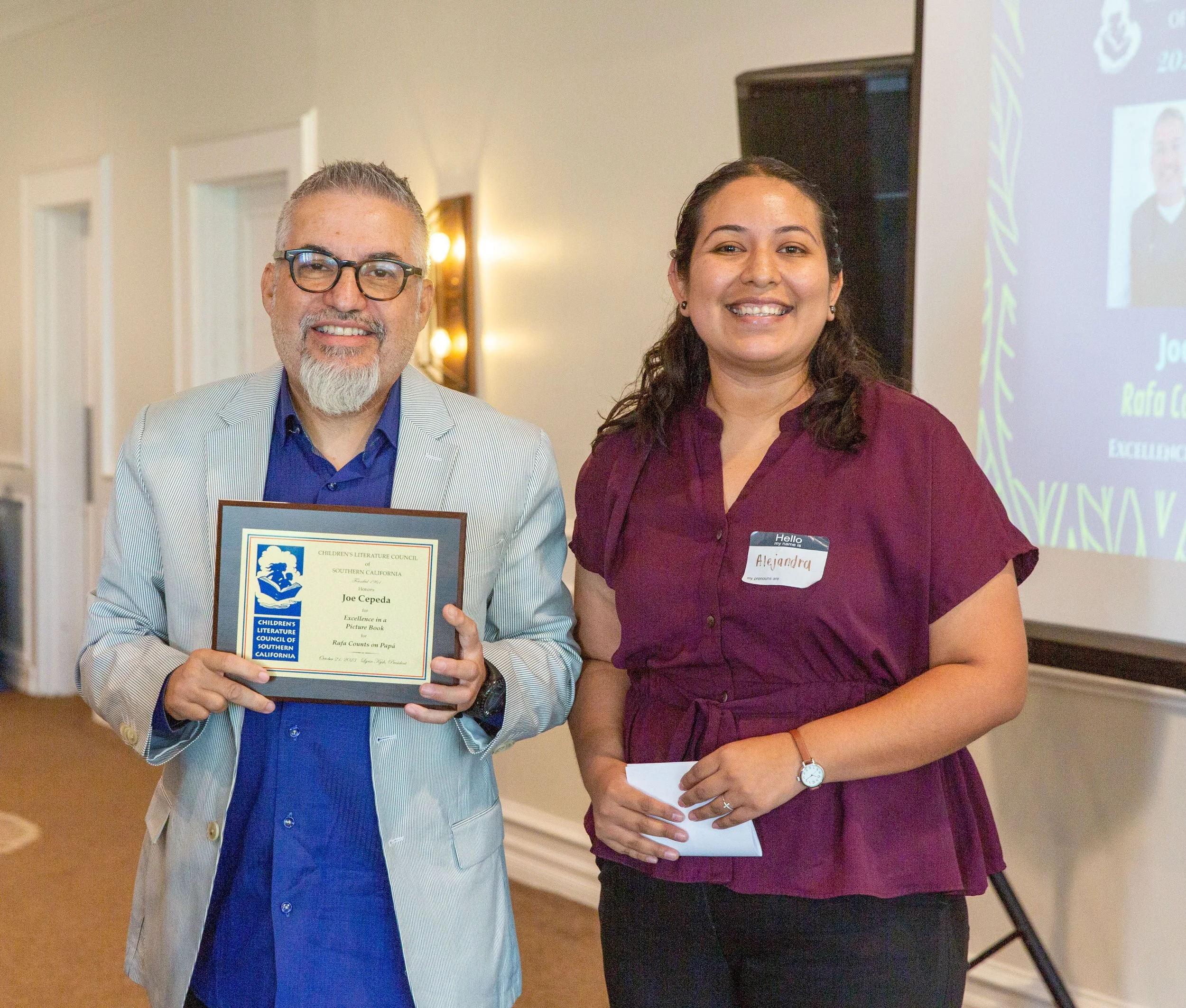 Winner Joe Cepeda (left), holds up his award plaque. On the right is CLCSC Awards Committee Member Alejandra Reyes. (Josh Steichmann)