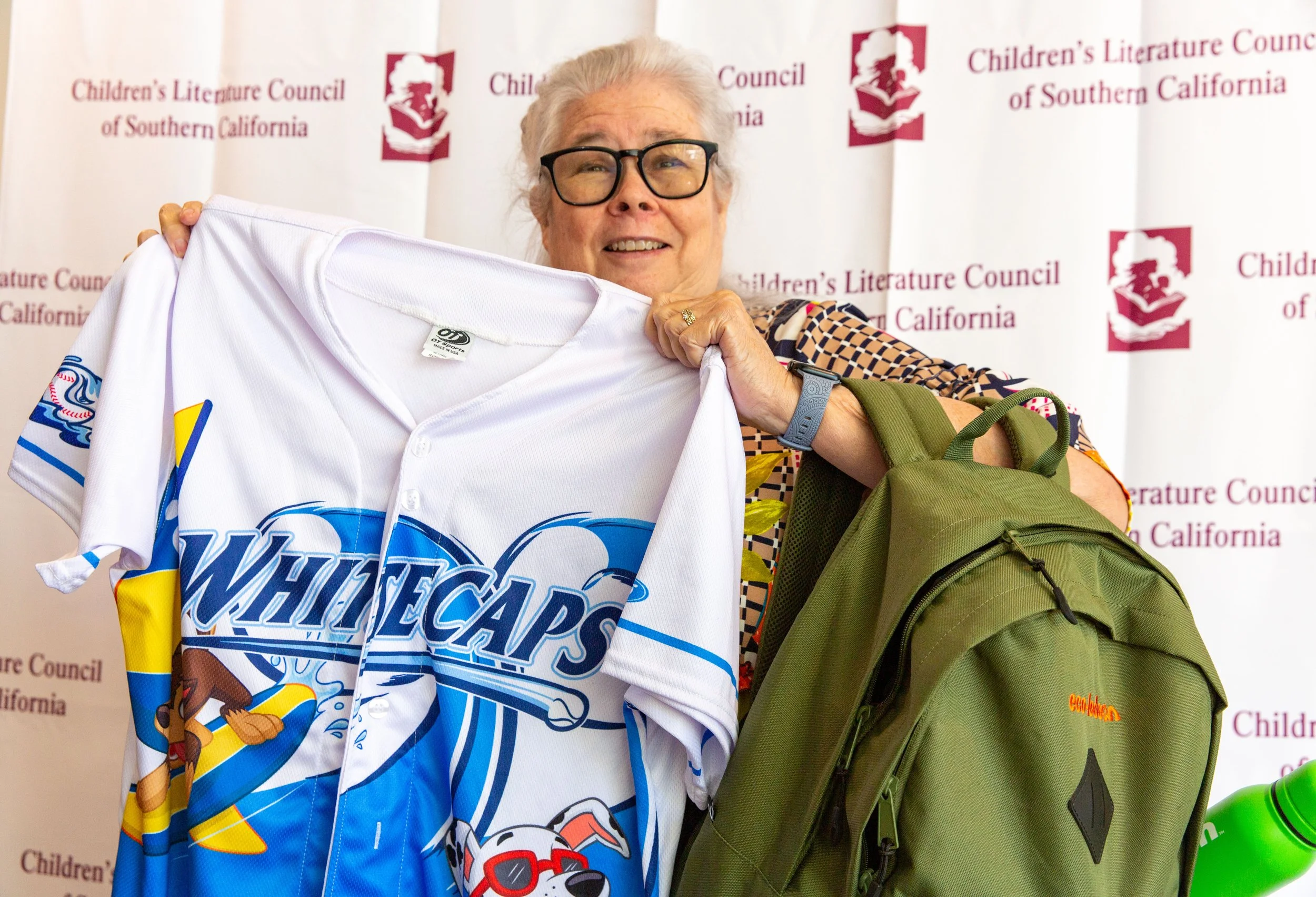 Silent auction winner Cathy Blackler displays a PAW Patrol jersey and an "ecolodeon"-branded backpack from Nickelodeon Animation Studio. (Josh Steichmann)