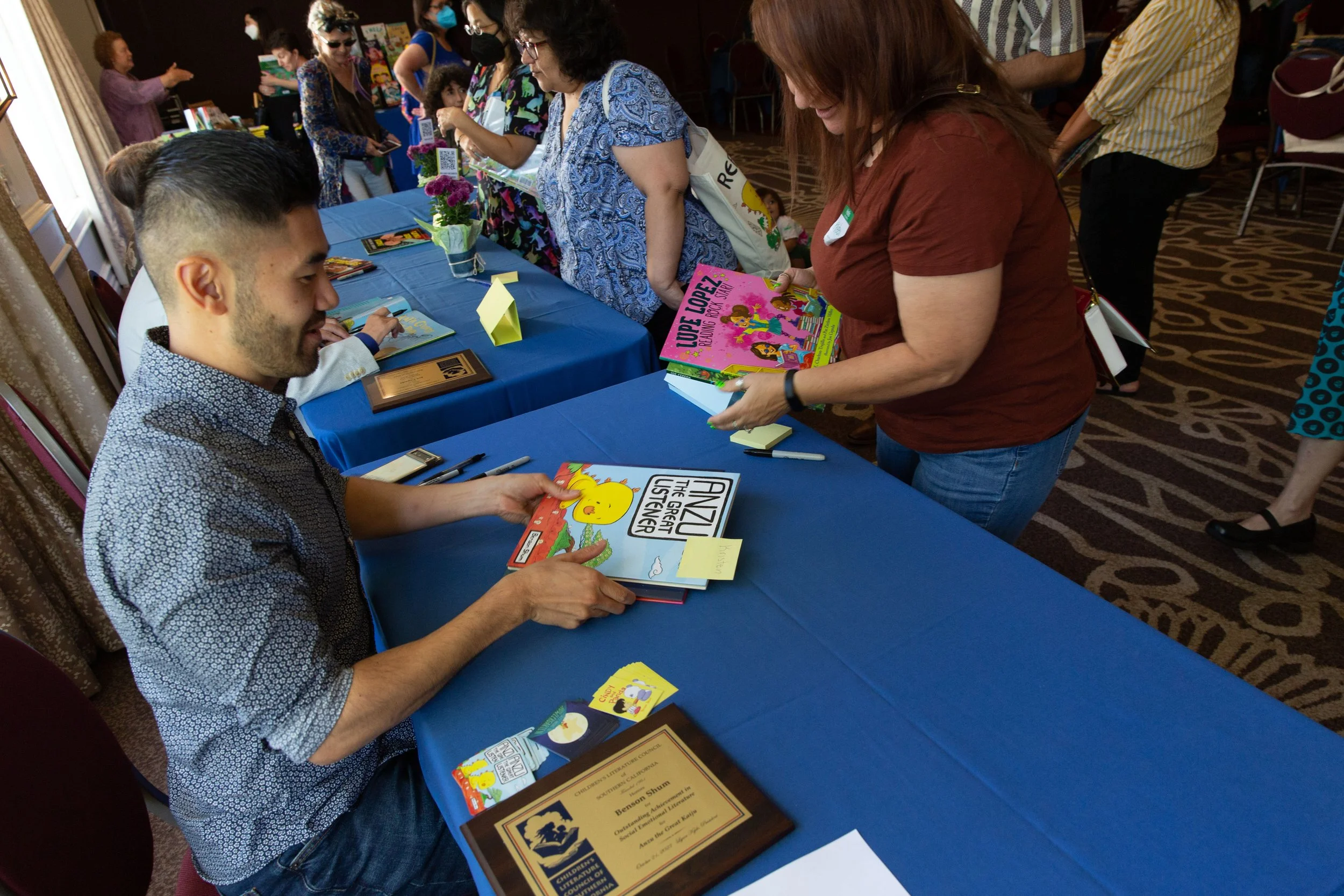 Author/illustrator Benson Shum signs a book and chats with attendee Kristen Valenzuela at the 2023 CLCSC Awards Ceremony. (Josh Steichmann)
