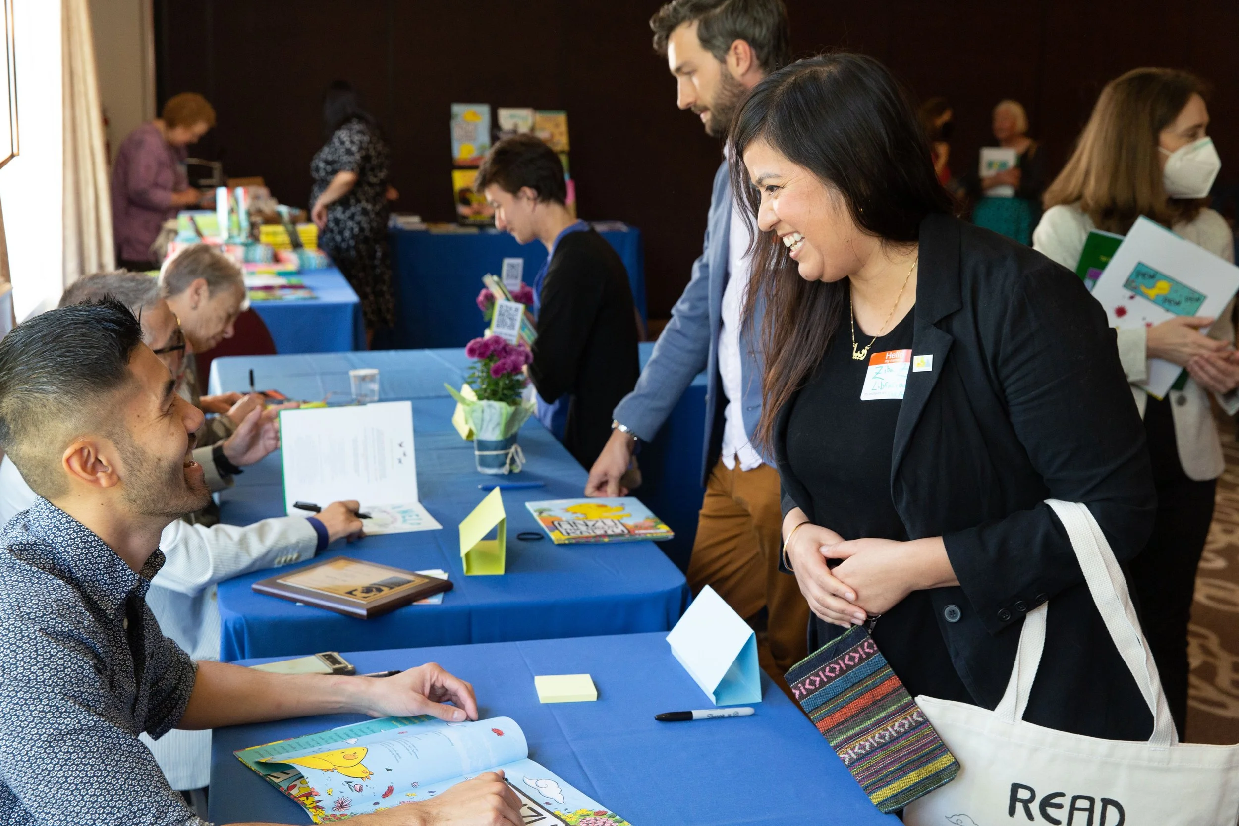 L to R: Author/illustrator Benson Shum chats with librarian Ziba Perez. Behind them (F to B), Joe Cepeda and Caroline Arnold sign books for Kyle Horne and Annalisa Engh. (Josh Steichmann)