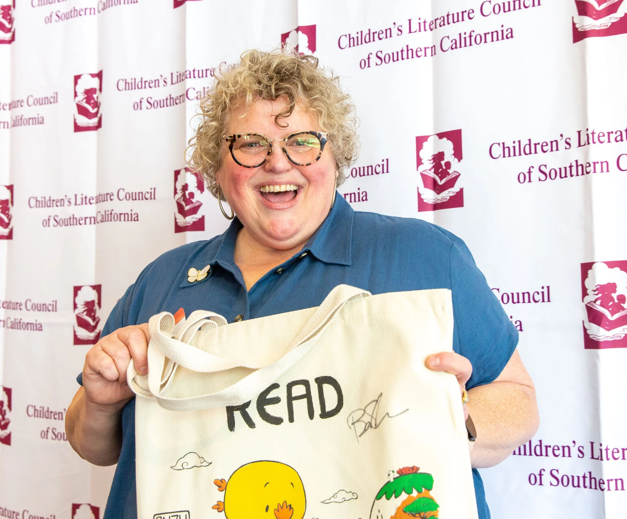 Danica Sheridan smiles and holds up her Anzu the Great Kaiju "Read" tote bag (Josh Steichmann)