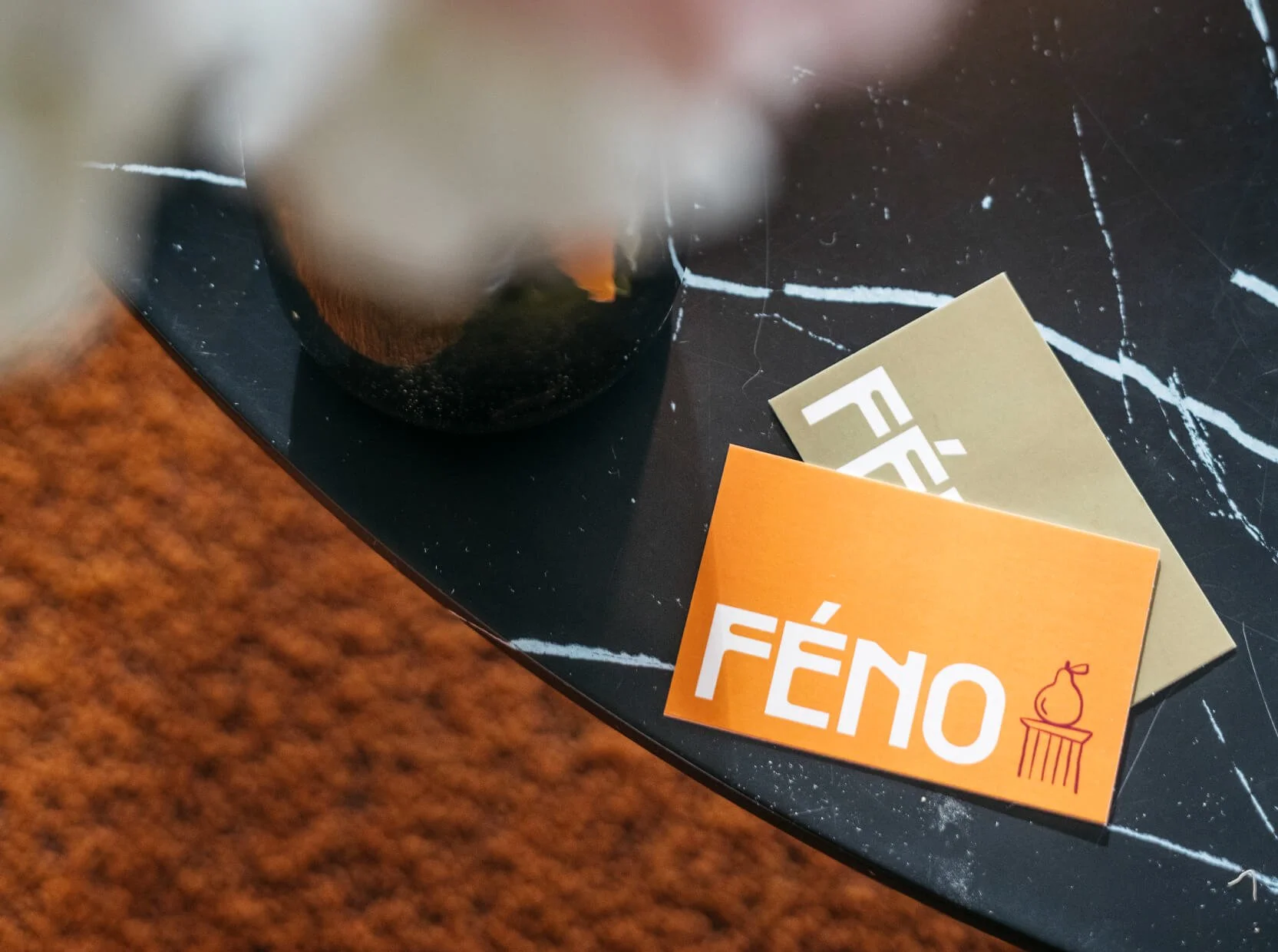 Deux cartes de visite du restaurant de Féno posées sur une table en marbre