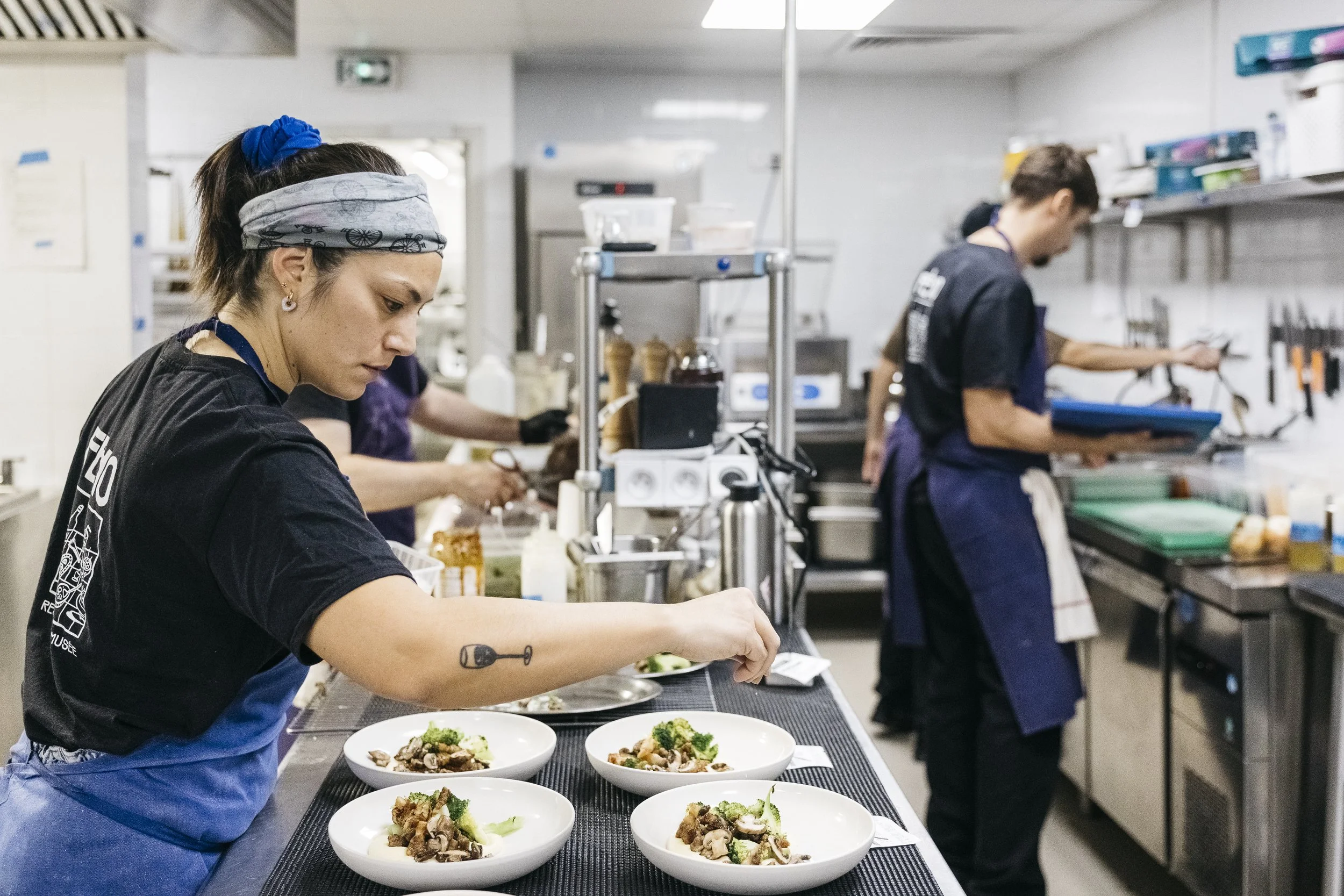 Deux chefs de cuisine préparent des plats dans une cuisine professionnelle.