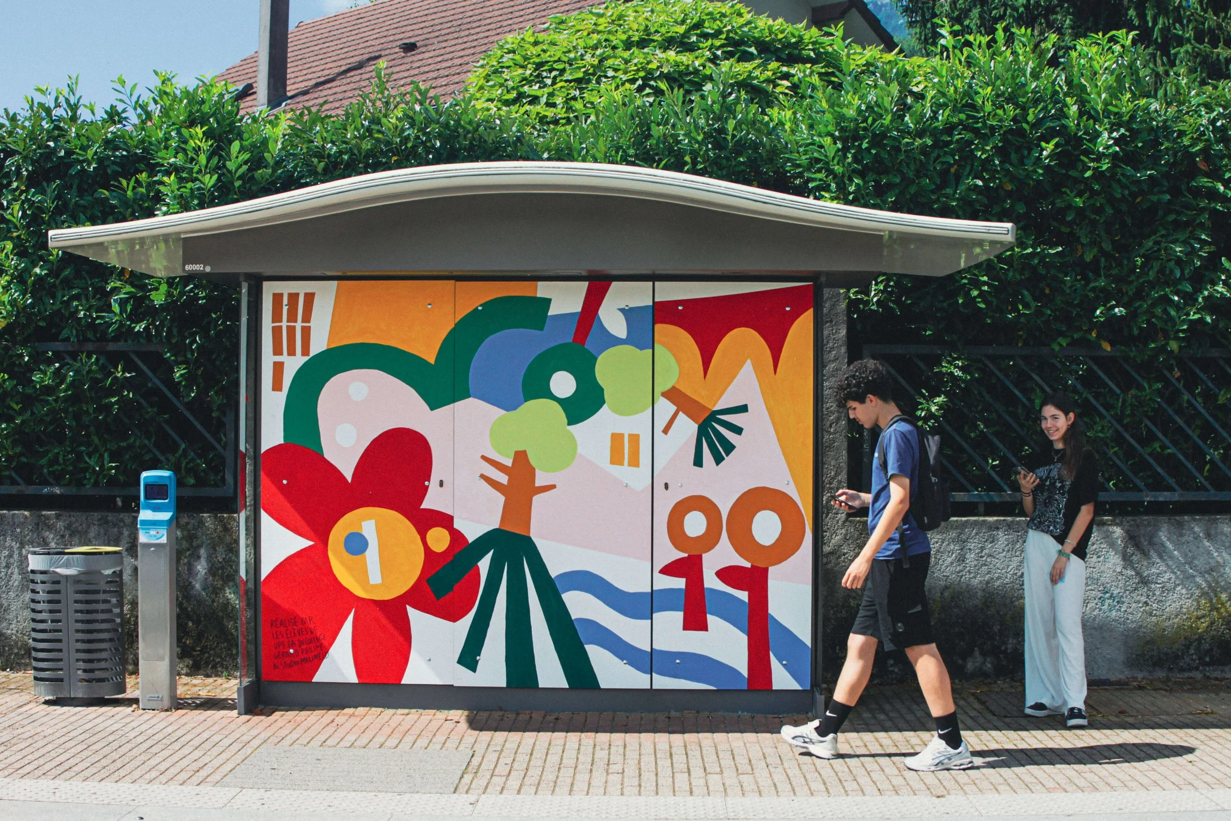 Un garçon passe devant la fresque de l'arret de tram de Charles Michel