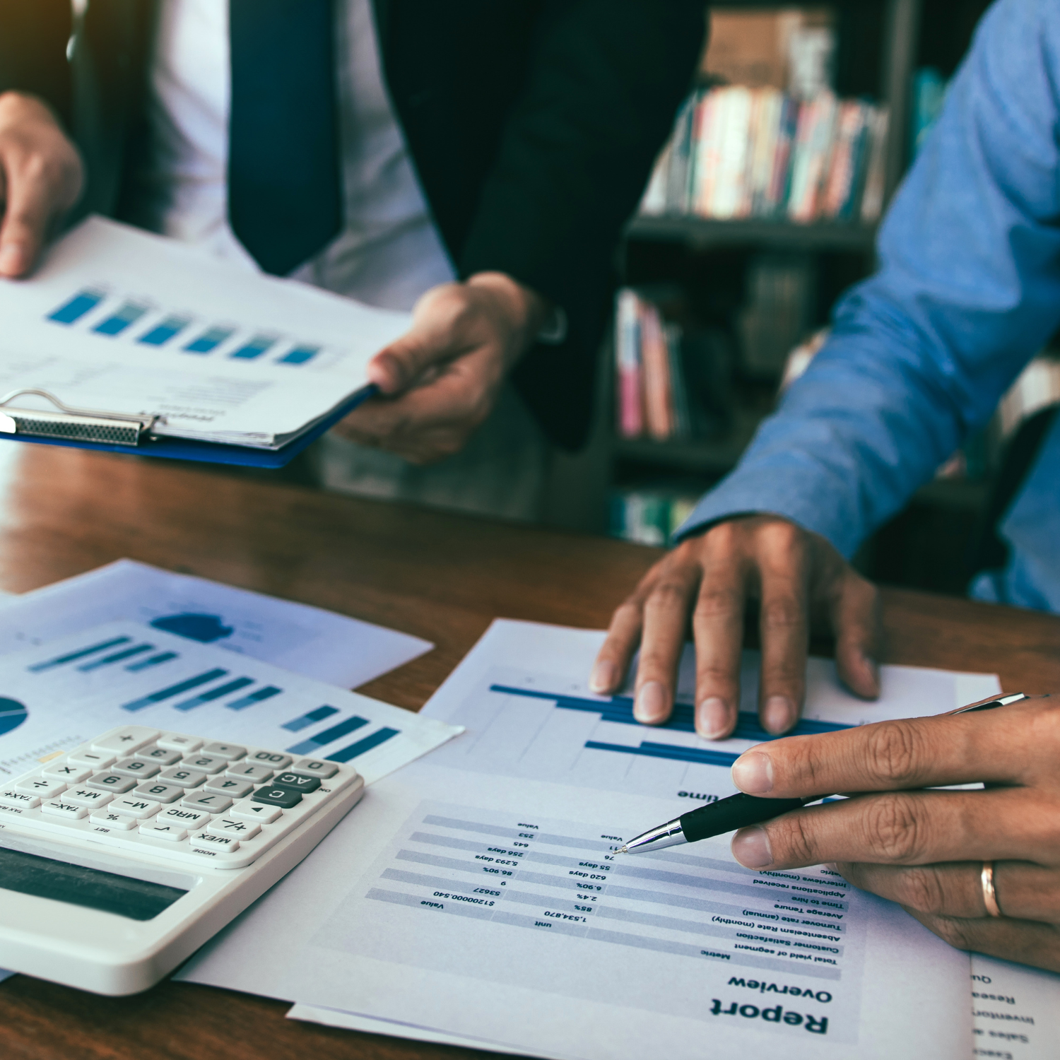 Business meeting analyzing financial reports with graphs and calculator