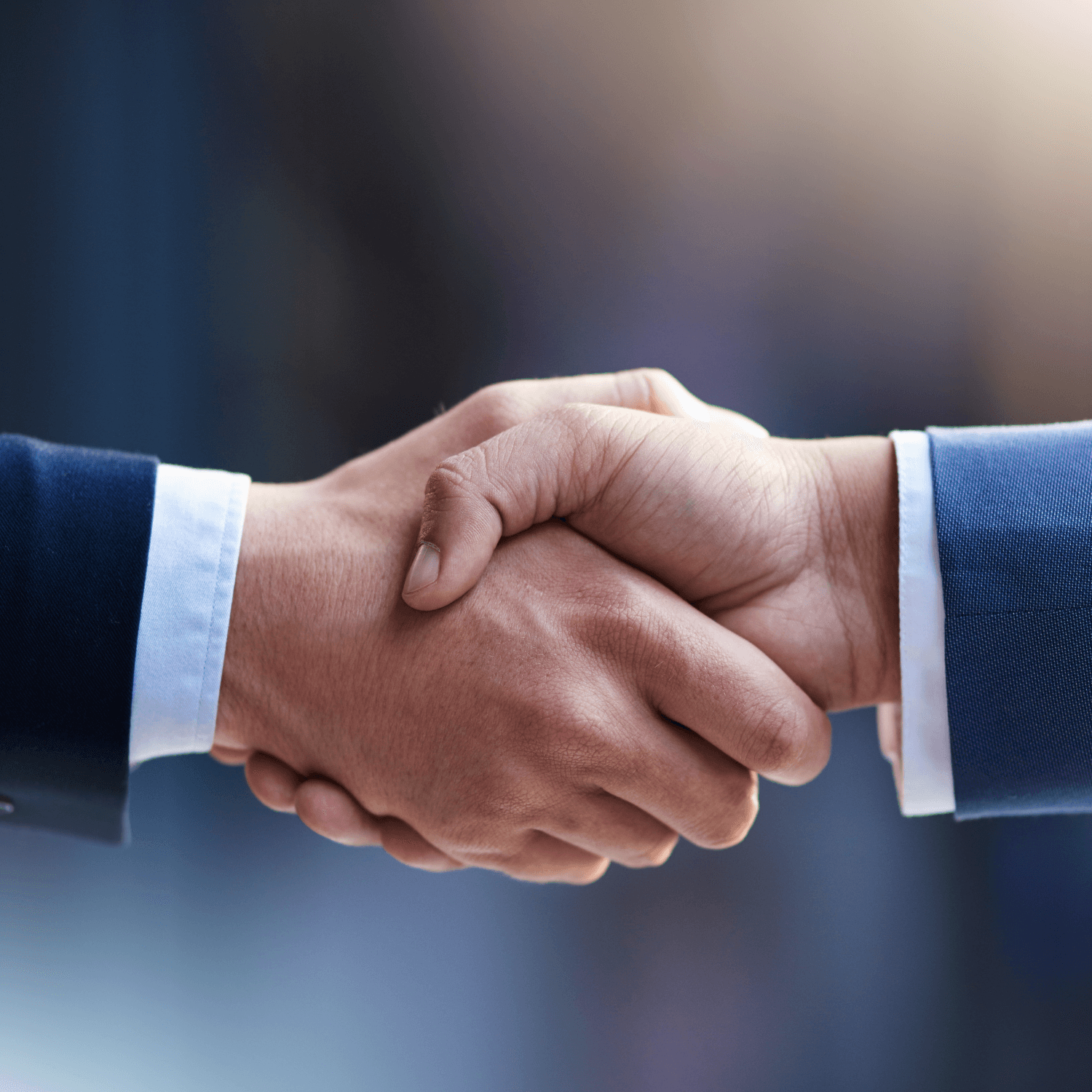 Two people shaking hands, wearing business suits, symbolizing a professional agreement or partnership.