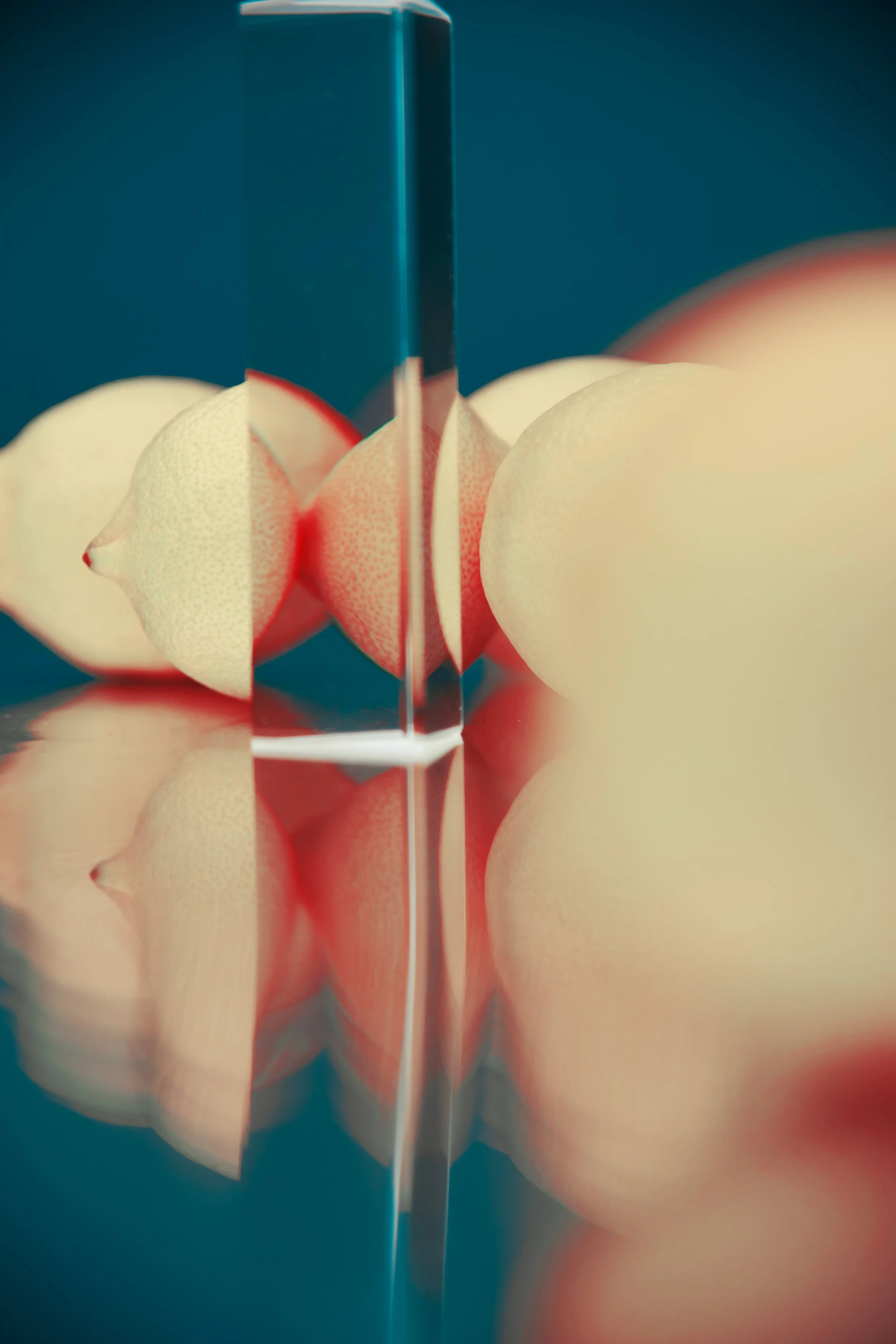 A close-up view of a blade cutting through a radish, with the radish's interior exposed, reflected on a glossy surface.