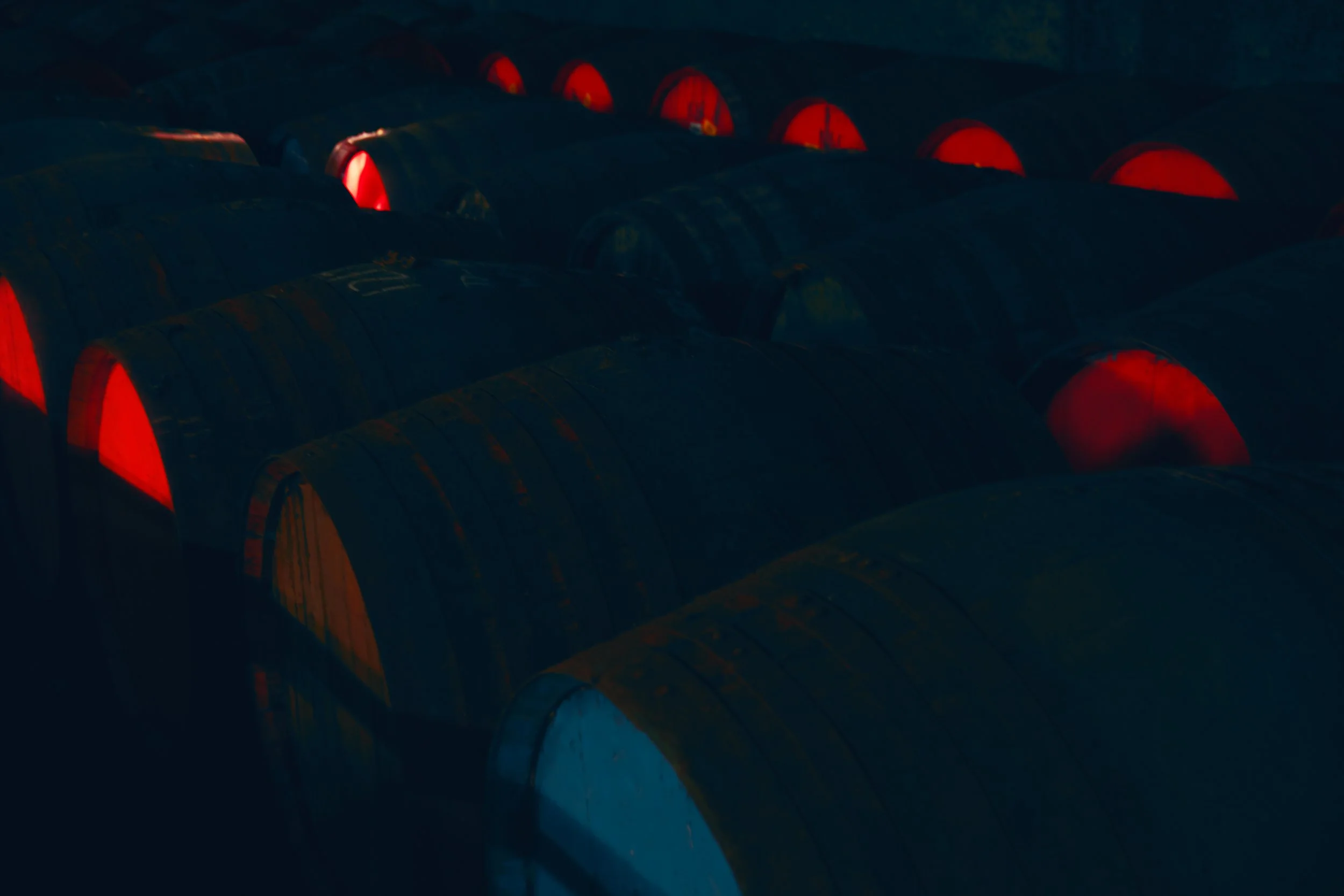 Multiple black cylindrical objects with red ends, arranged in rows in a dark setting.