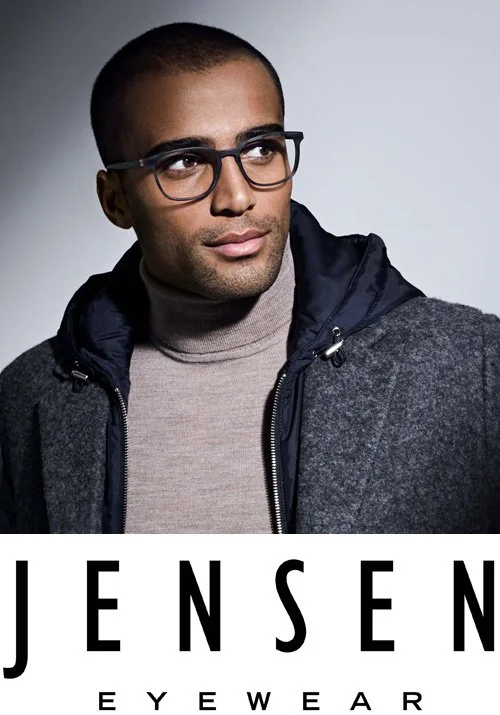 A man with short hair, glasses, and a slight beard wearing a gray turtleneck and a dark jacket, looking to the side against a plain background. The image has text at the bottom that reads 'JENSEN EYEWEAR.'