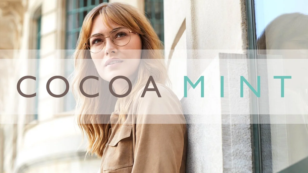 A woman with reddish hair and glasses standing against a building wall, with the words 'COCOA MINT' overlaid.
