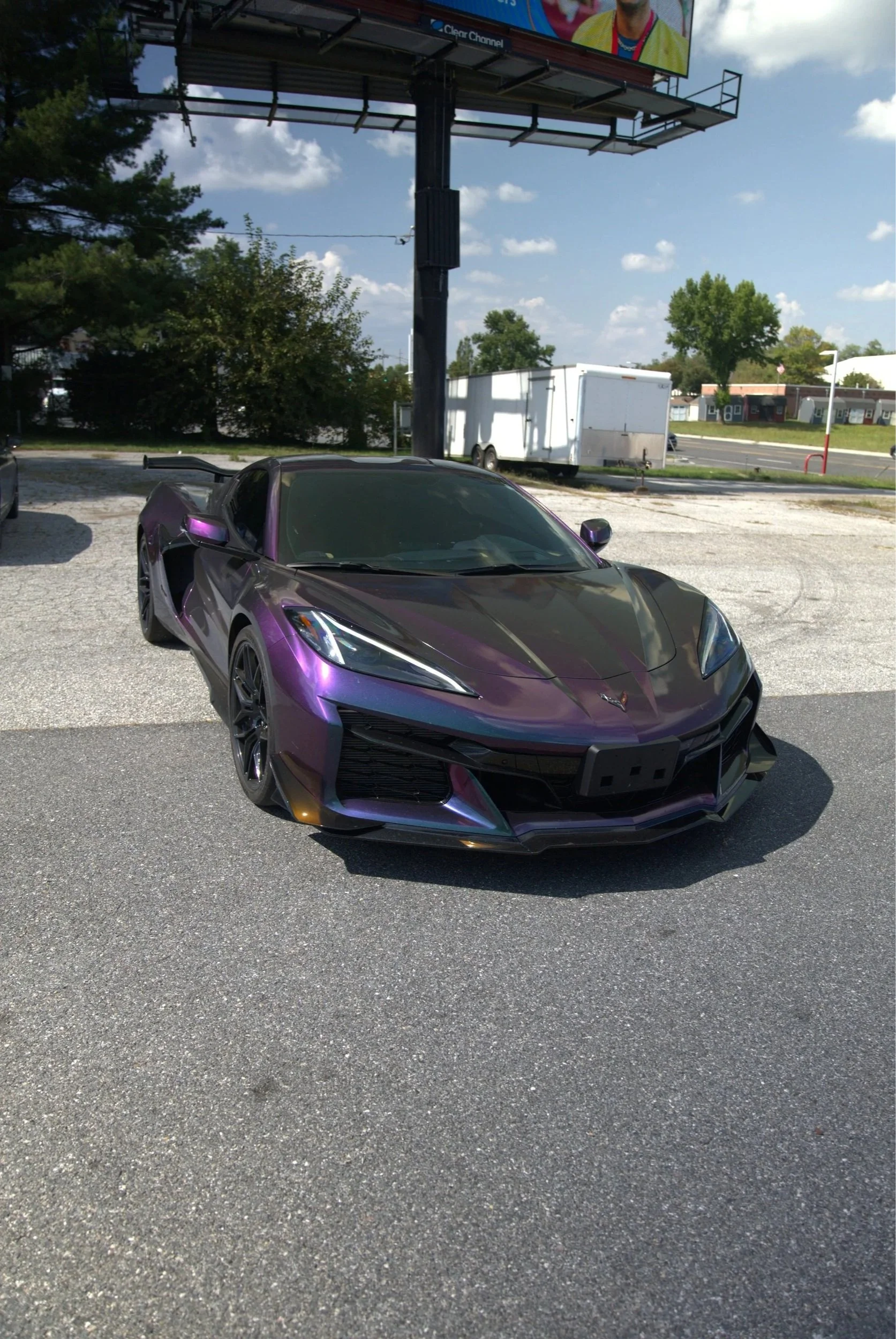 A purple and black sports car parked on a gravel lot.