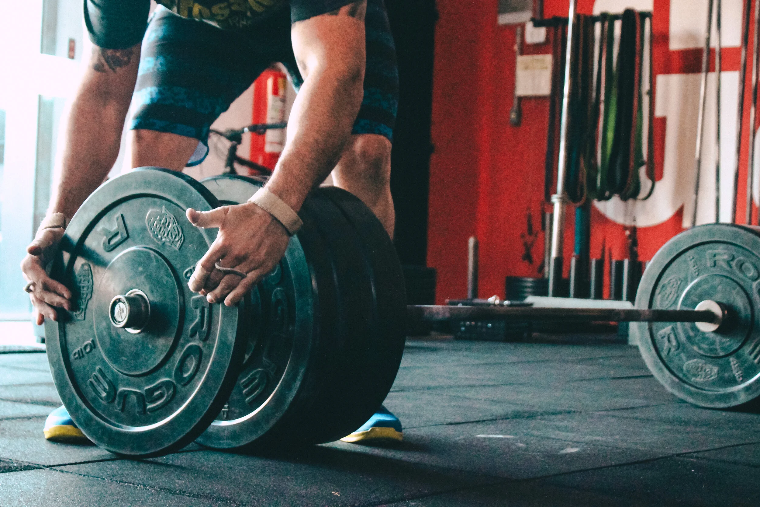 Man loading barbell with weights indoor gym