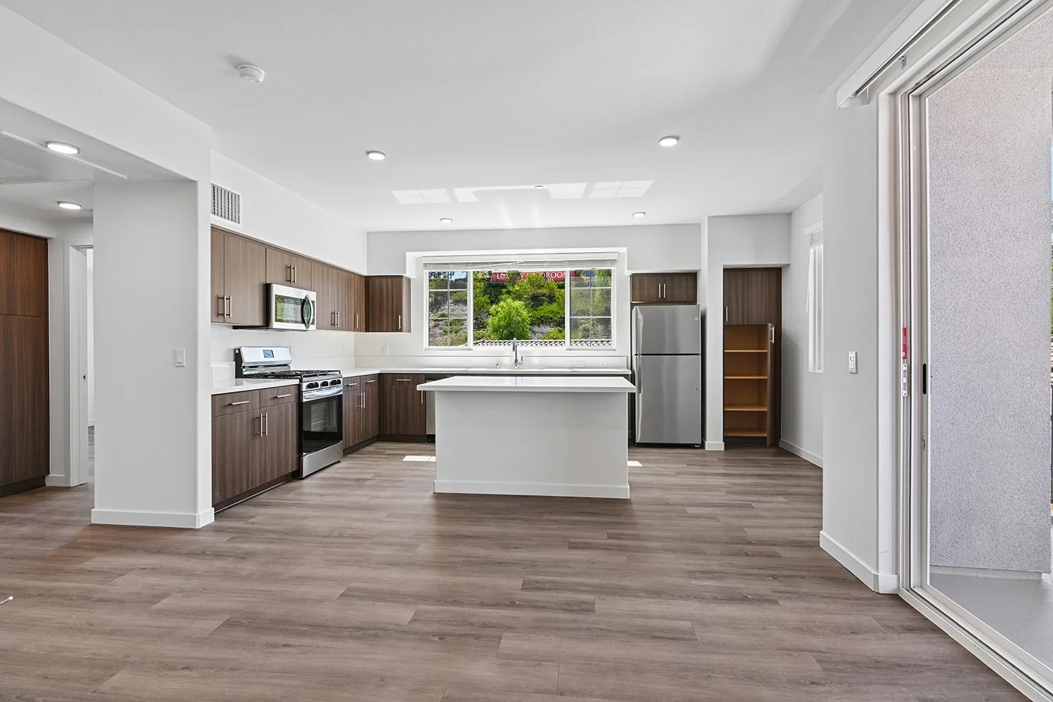 Beautiful and spacious unit at Rendezvous Phase II with wood style plank flooring, island, quartz countertops, modern dark wood cabinetry, and stainless steel appliances. 