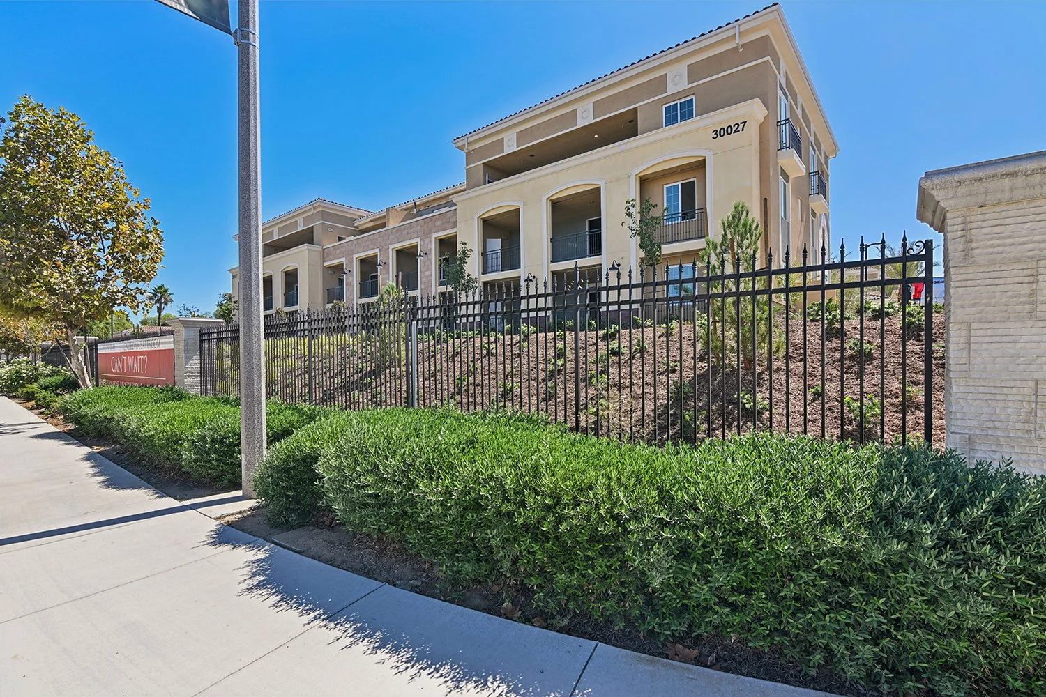 Grand exterior of Rendezvous Phase II standing behind iron gate lined with lush landscaping.