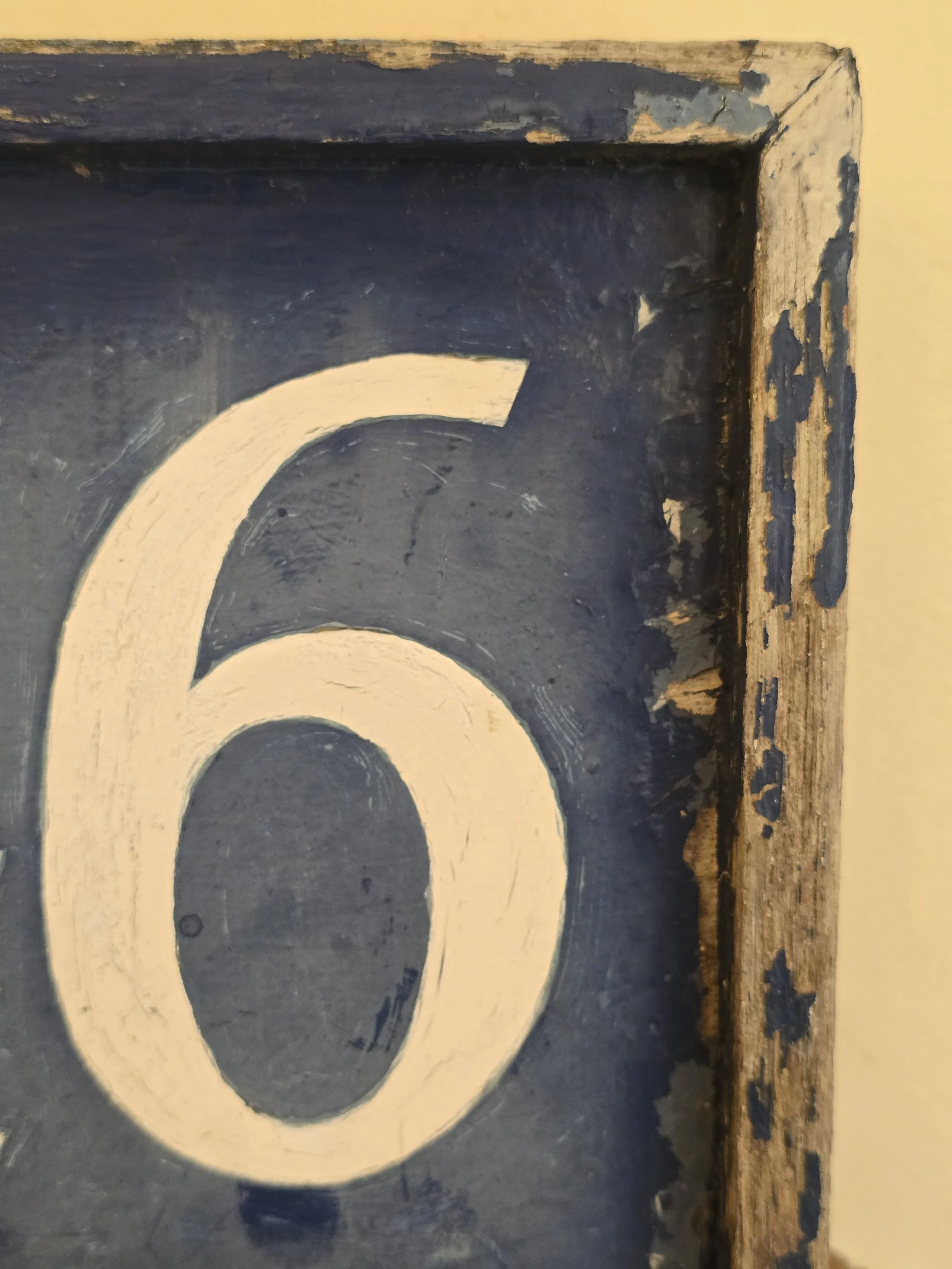 Rustic wooden house number plaque with cream numerals and aged blue finish.
