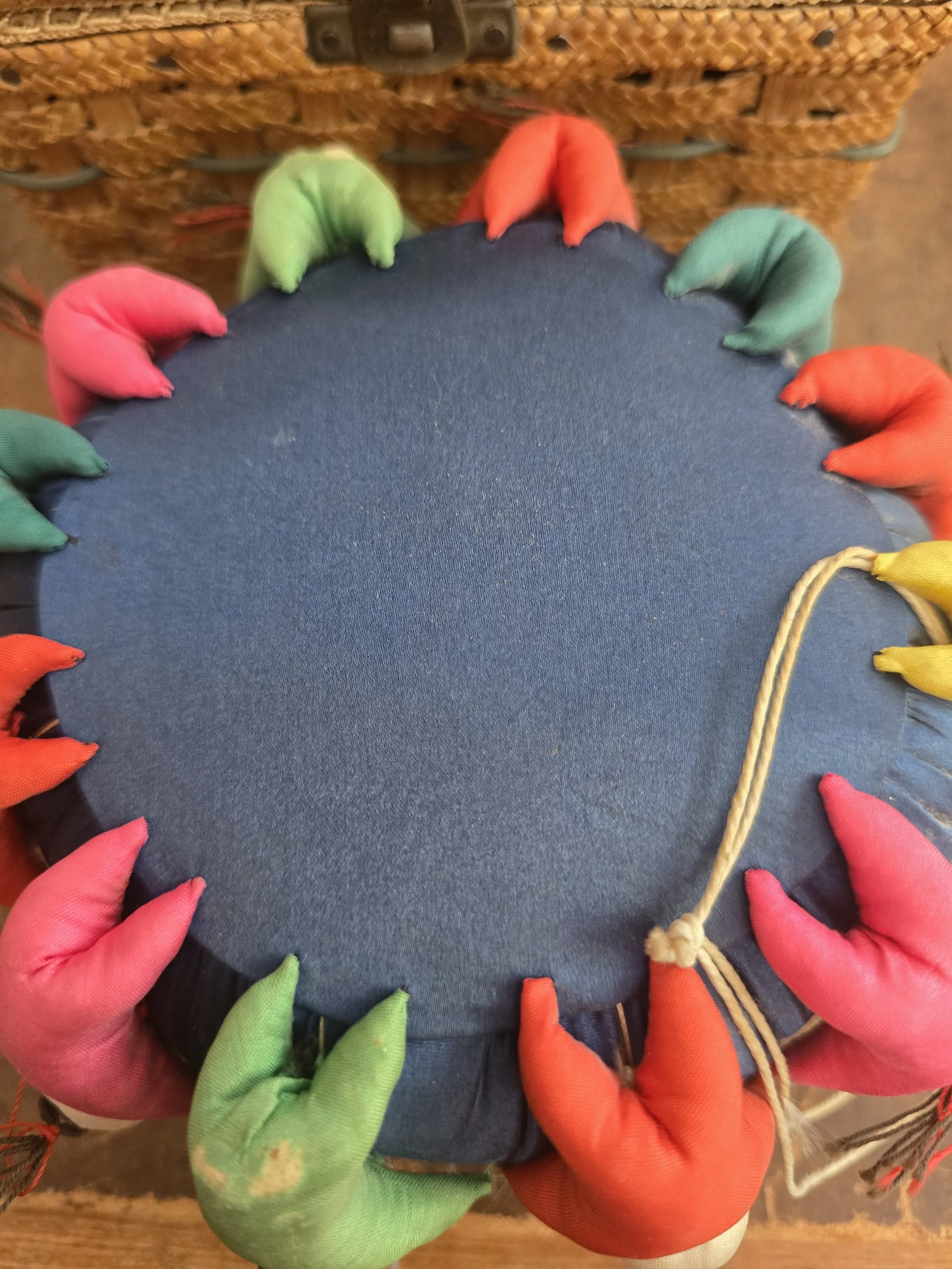 Decorative pin cushion with fabric doll faces around the edge.
