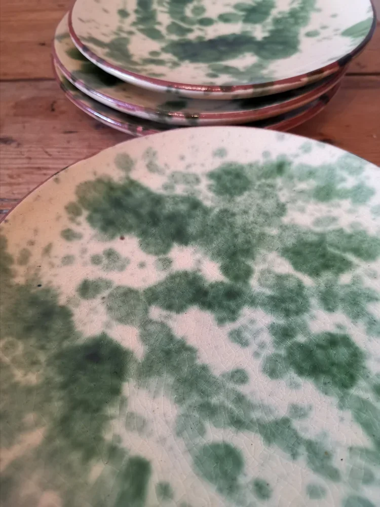 Angled view of handmade Provençal plates with green mottled glaze
