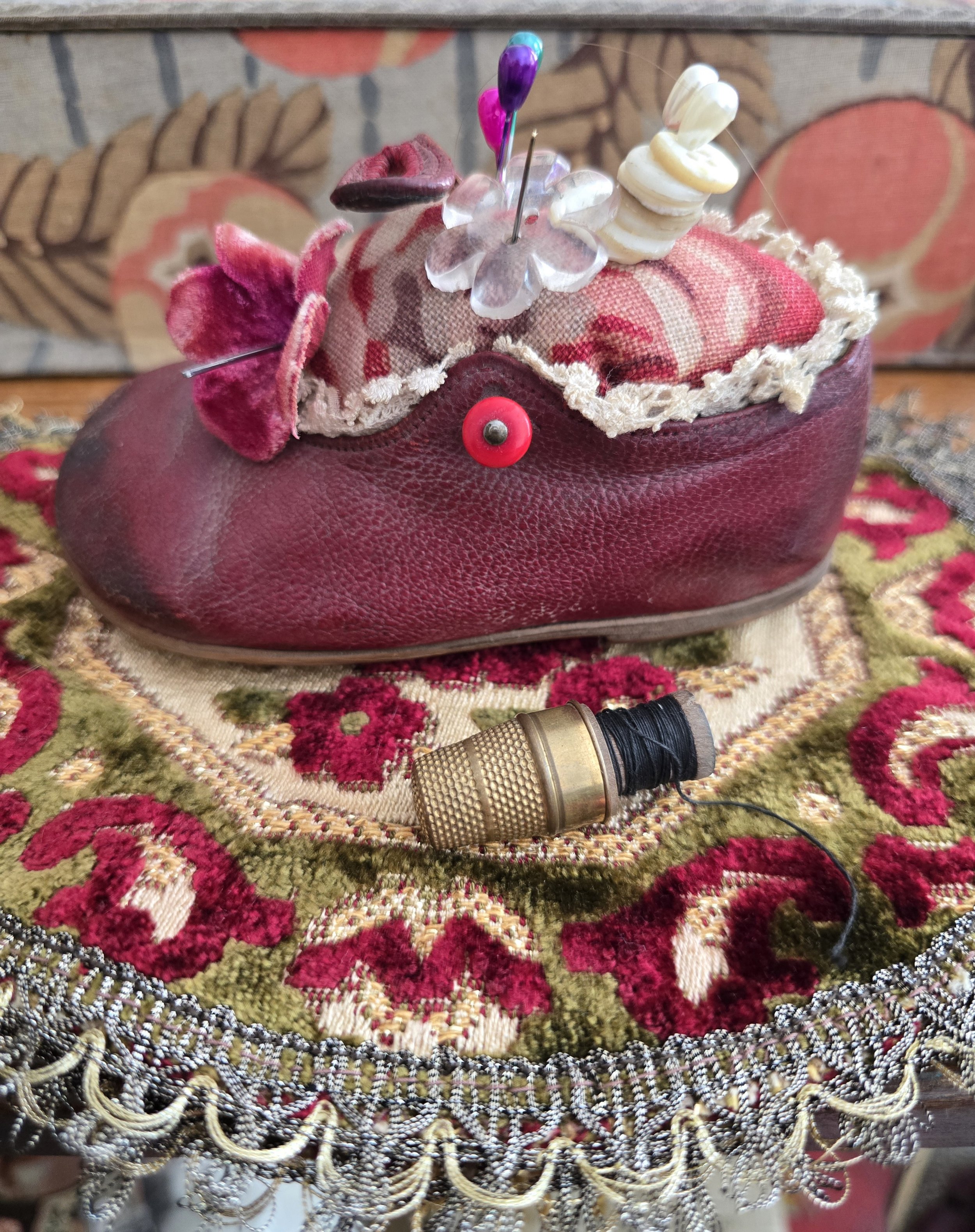 Antique French child's leather shoe transformed into a decorative pin cushion with vintage floral linen.