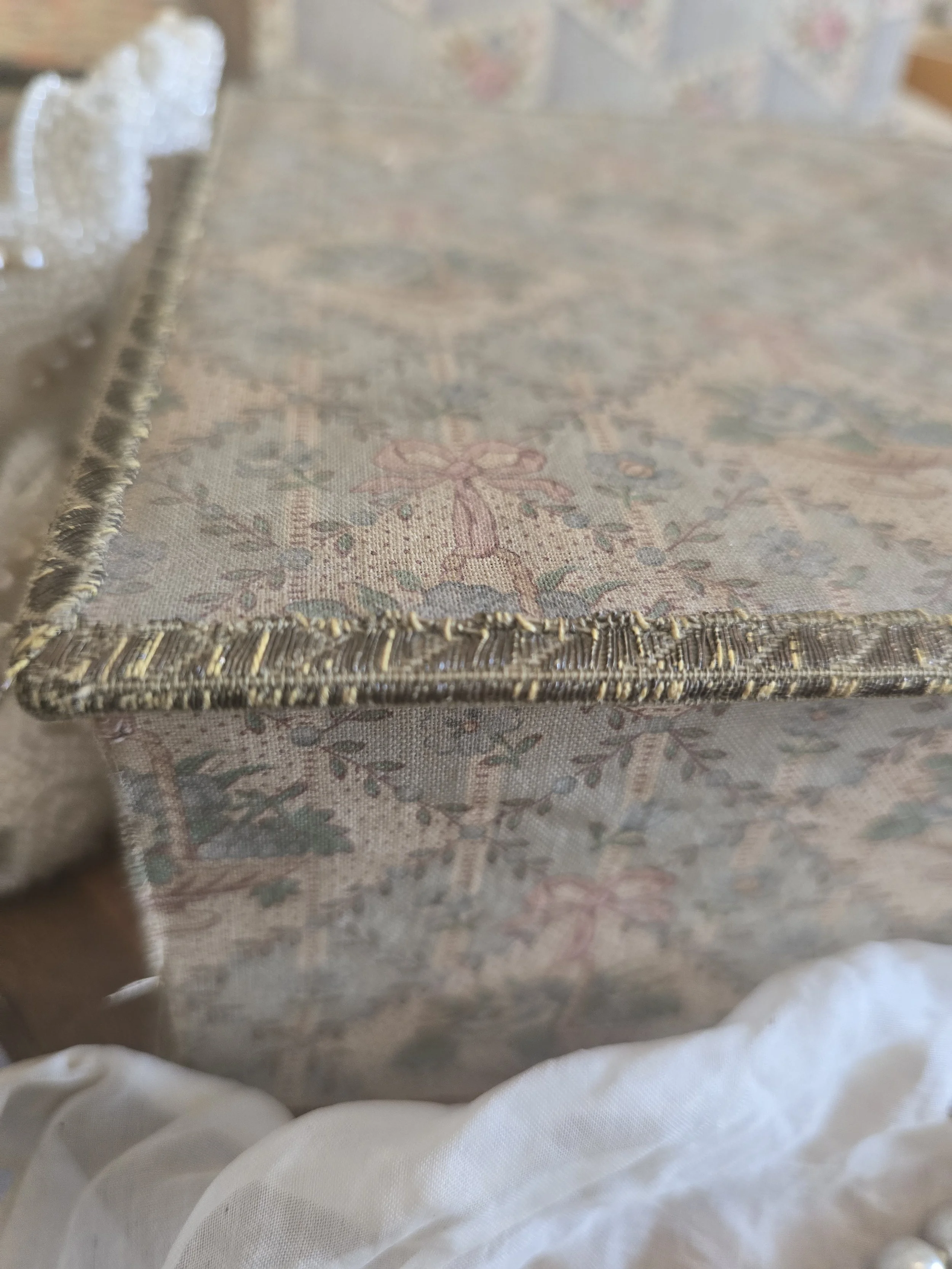 Front view of antique French fabric-covered box with blue roses, pink ribbon bows and original metallic trim.