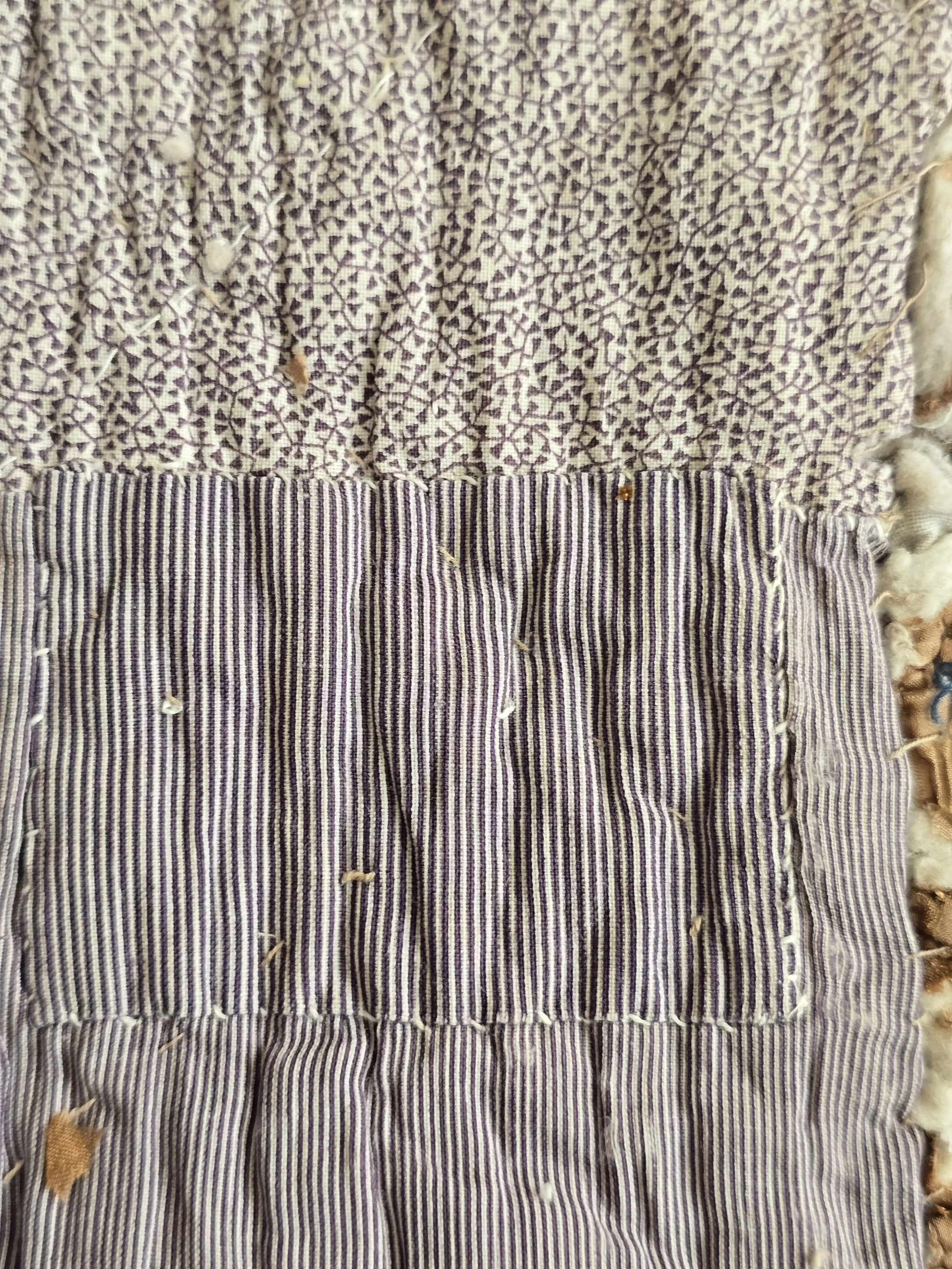 Antique French quilt fragment measuring 47 x 42 cm with faded purple printed cotton and exposed layers.