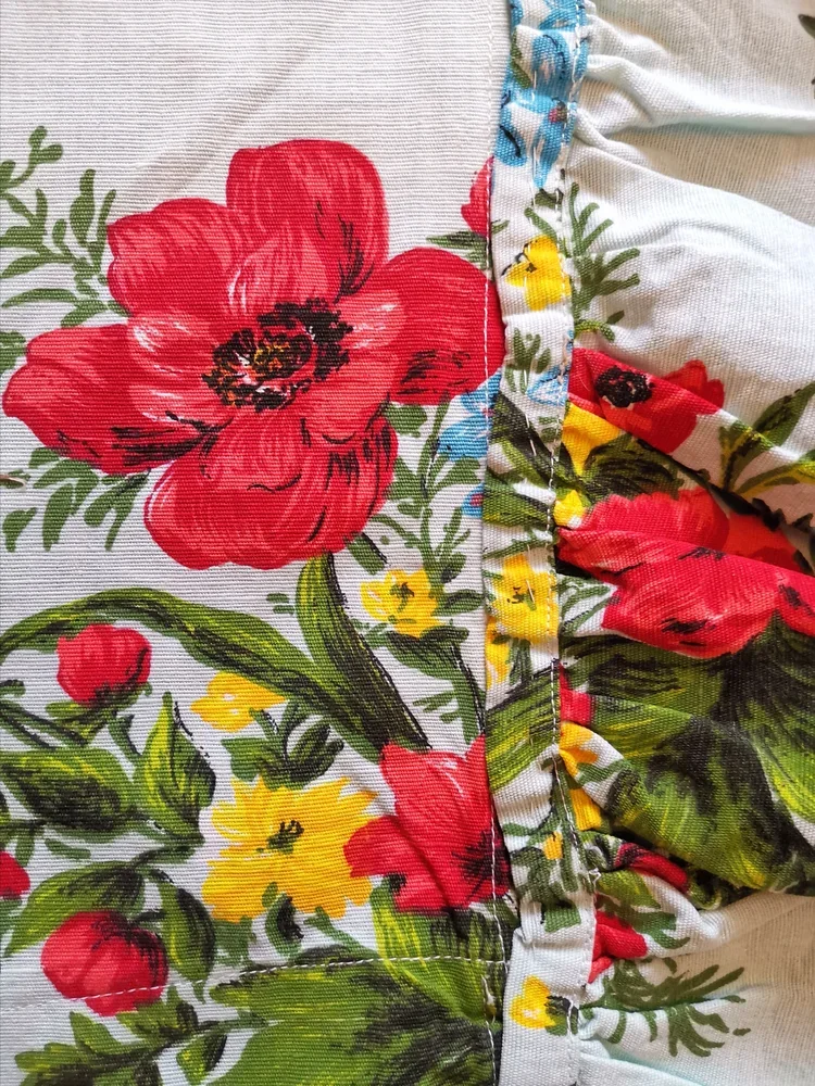 Vintage floral fabric featuring red poppy, yellow flower, and green foliage on white textured weave.