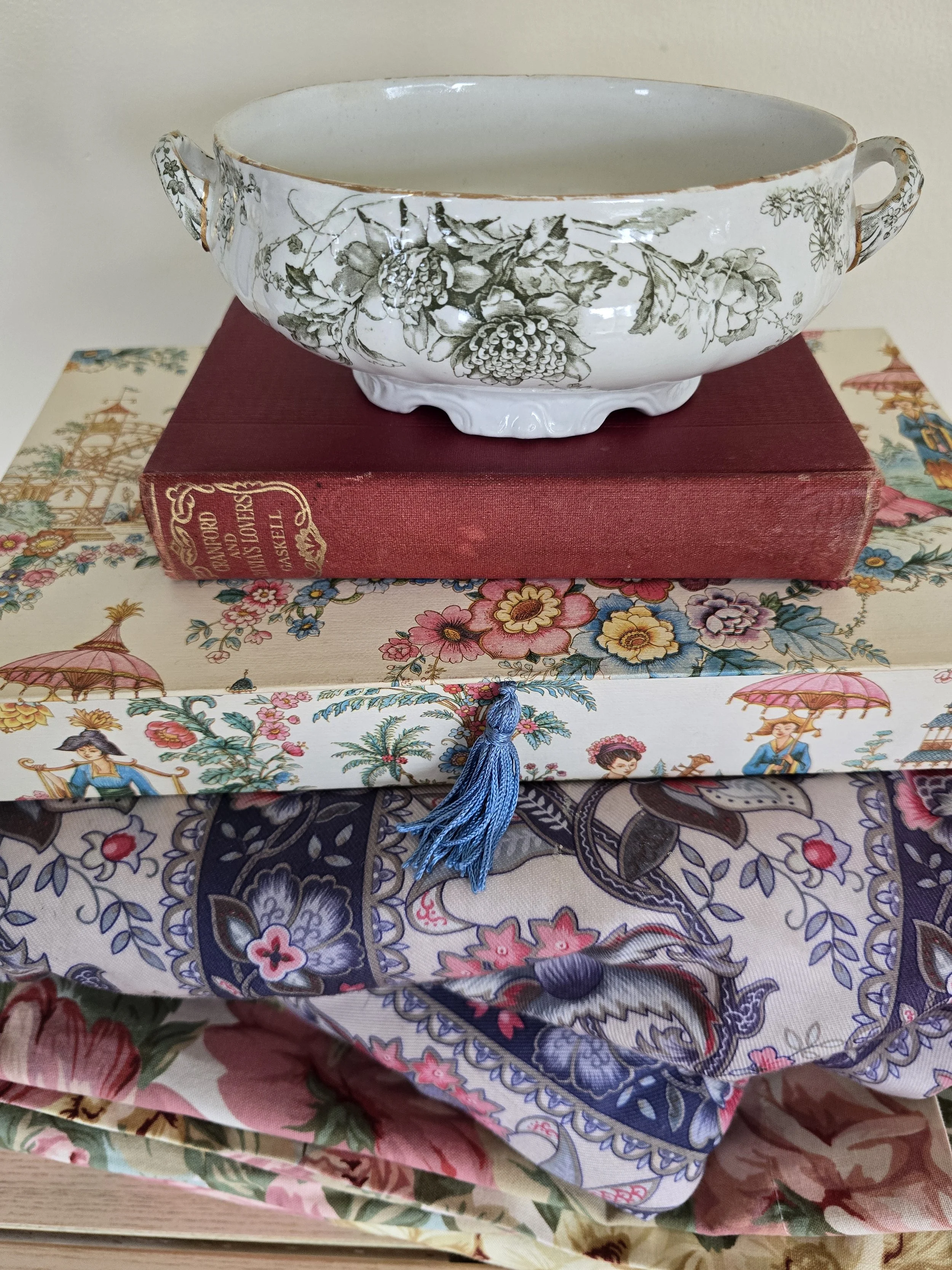 Vintage floral textiles, decorative books and an antique transferware bowl styled together by Pomme de Jour Vintage.