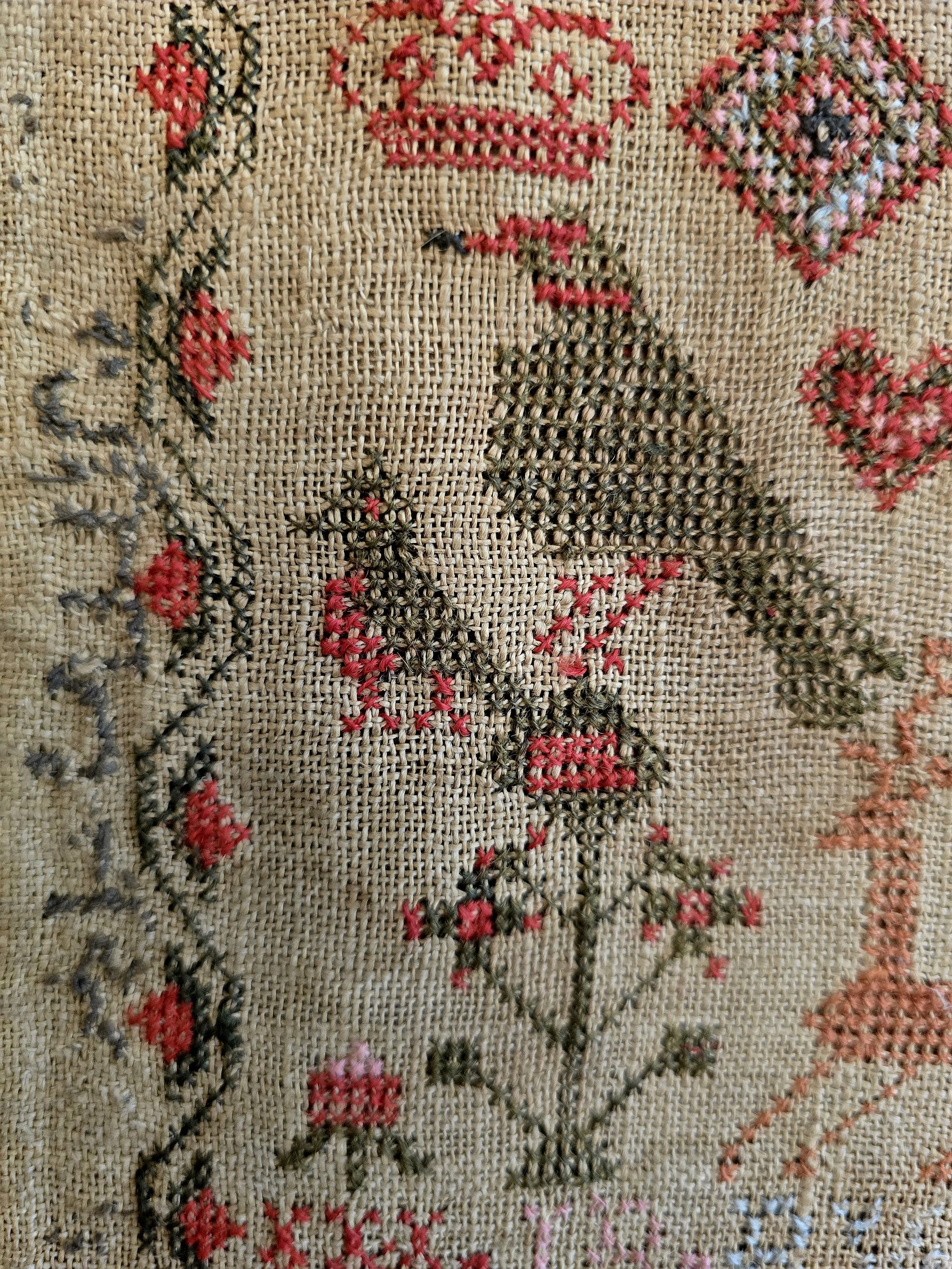 Detail of the embroidered birds, crowns and alphabet rows stitched in faded silk on Georgian linen.